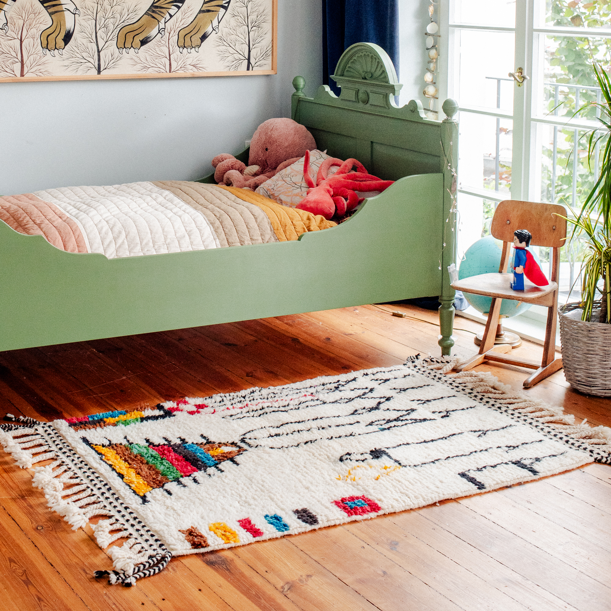 Modern Berber rug on floor beside a vintage green child's bed.