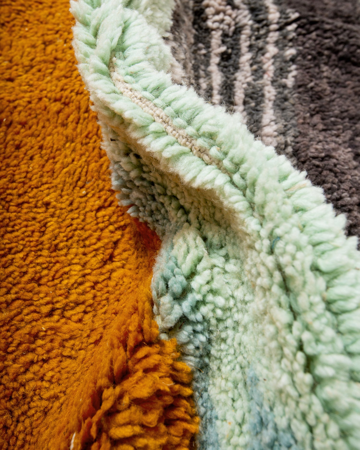 Close-up of textured turquoise, grey and orange wool rug.