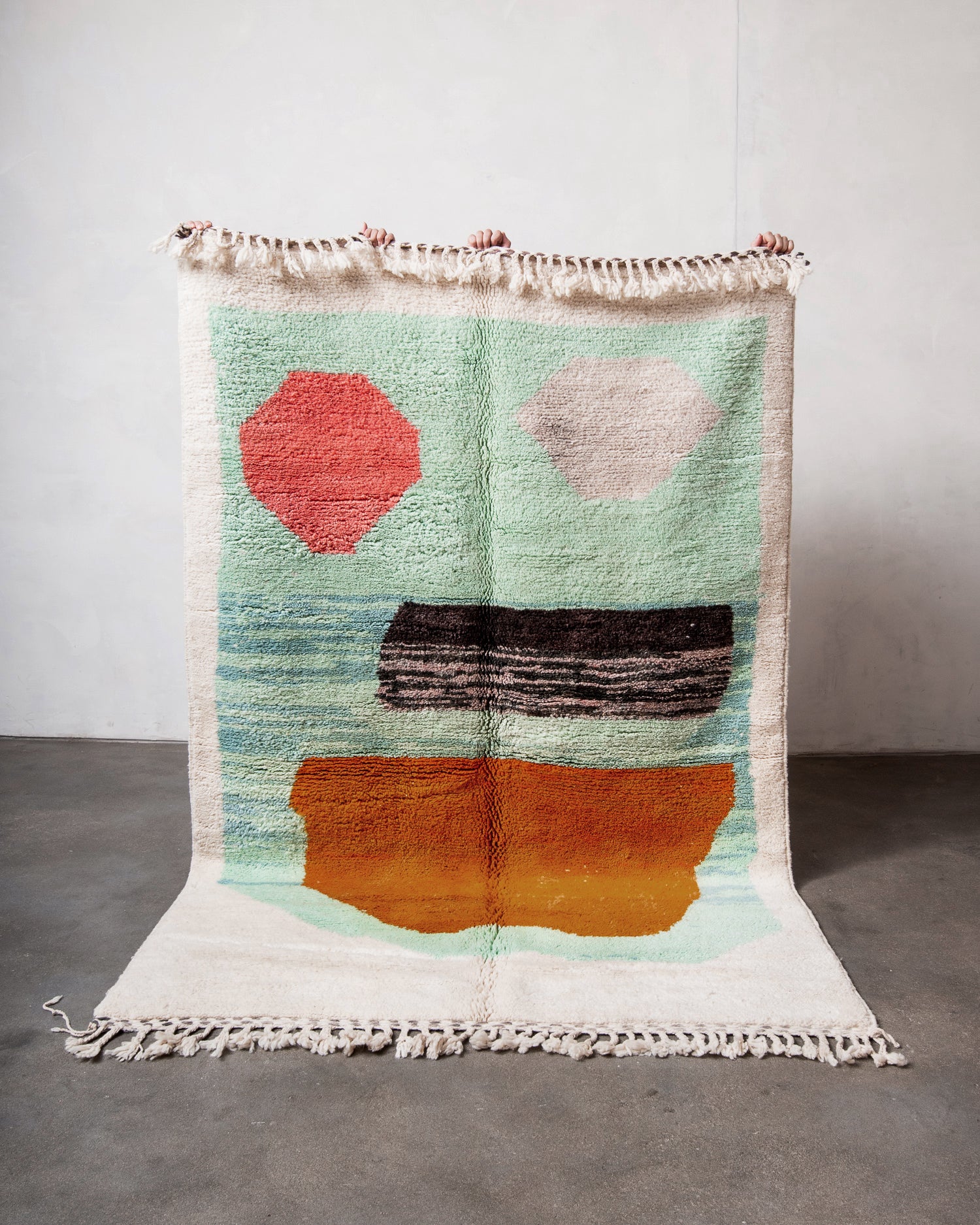 Colorful geometric-patterned rug with tassels on a plain background