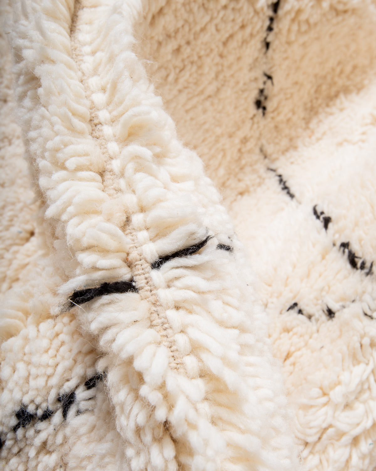 Close up of cream wool rug with black accents. 