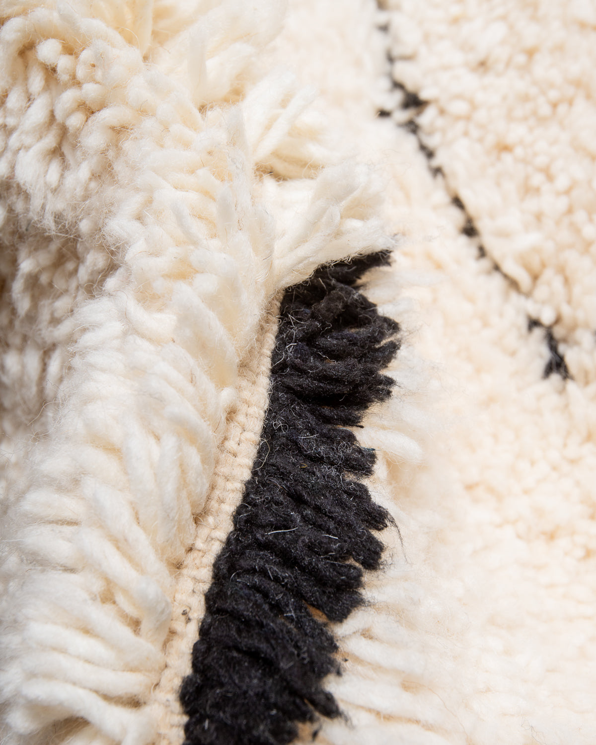 Close up of cream wool rug with black accents. 