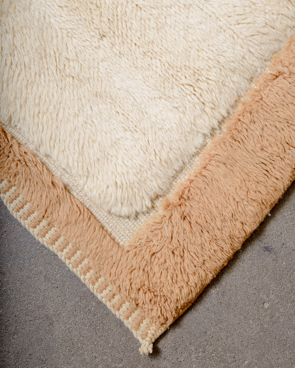 Corner of Beni M'rirt rug with the camel border separated from the cream area by a flat woven section.