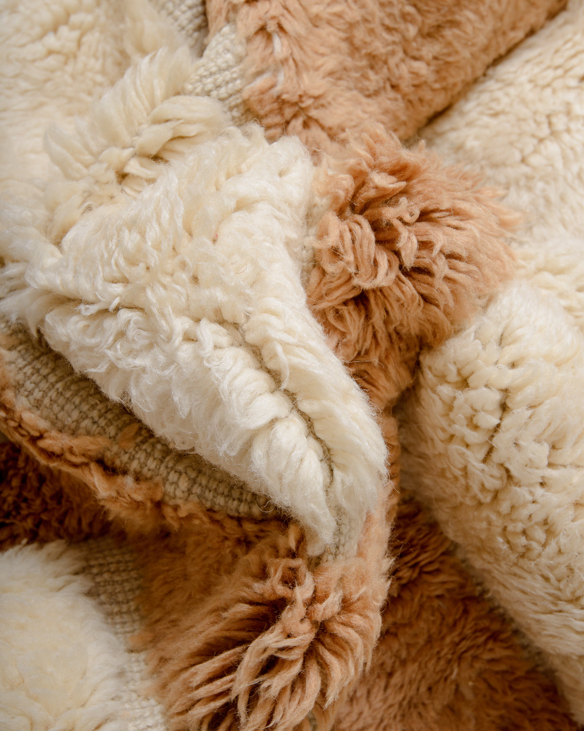 Close up of M'rirt rug made of fluffy wool in cream and camel with some flat woven sections.