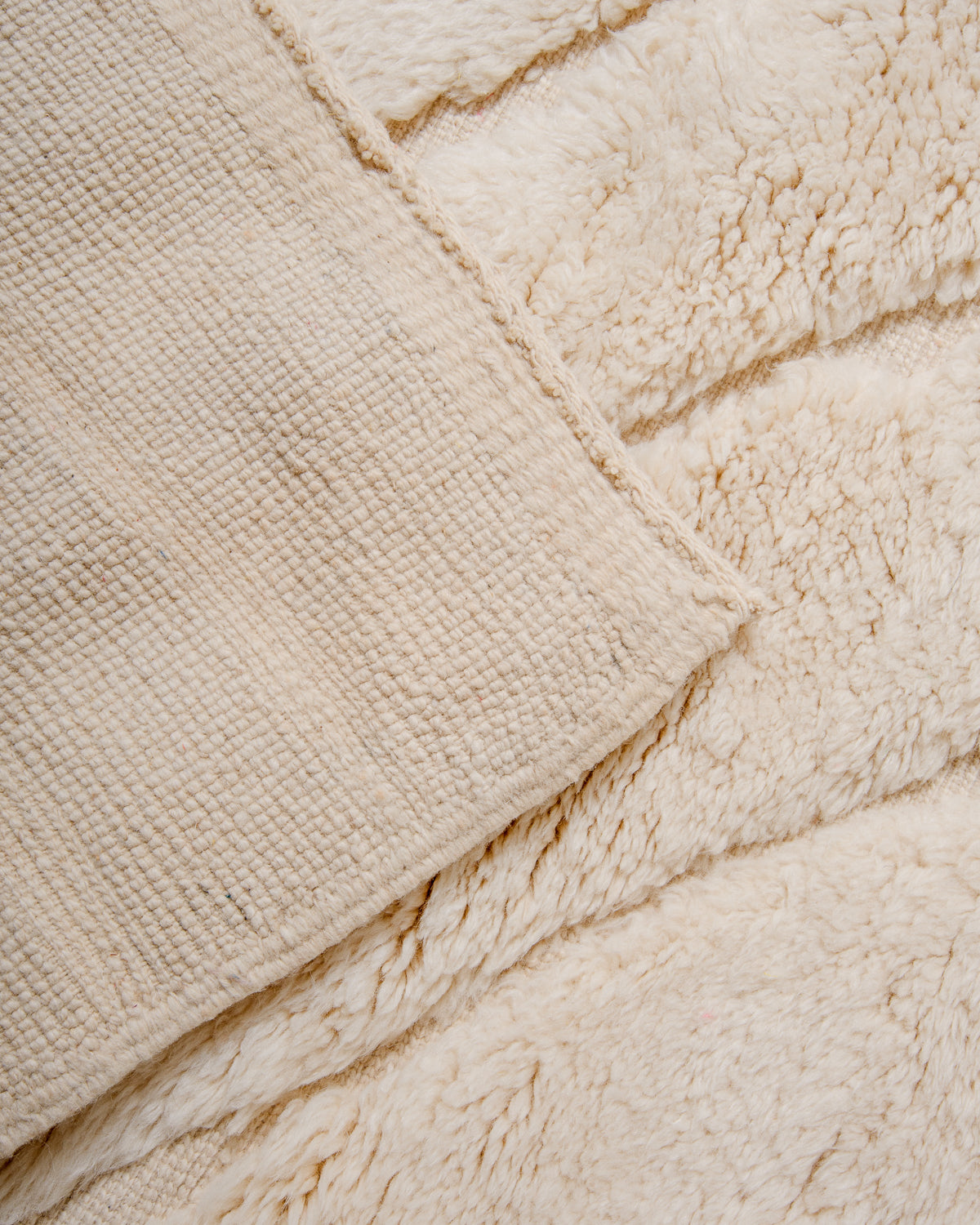 Corner of Beni M'rirt rug in cream wool folded over showing number of knots in the back of the rug.