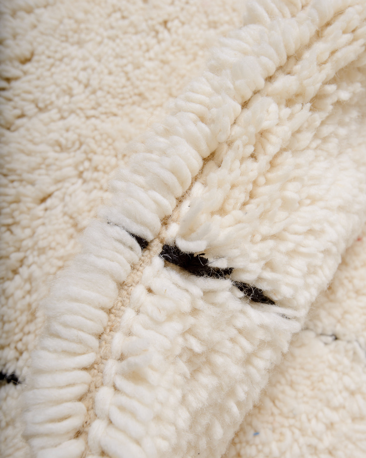Close up of cream wool rug with black accents. 