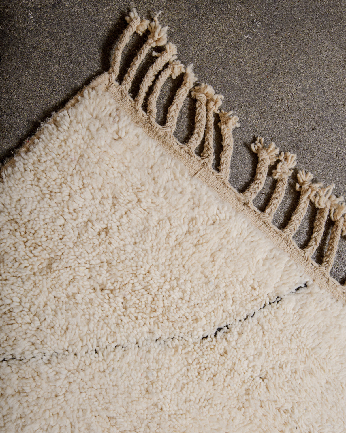 Natural wool tassels on edge of Berber rug.