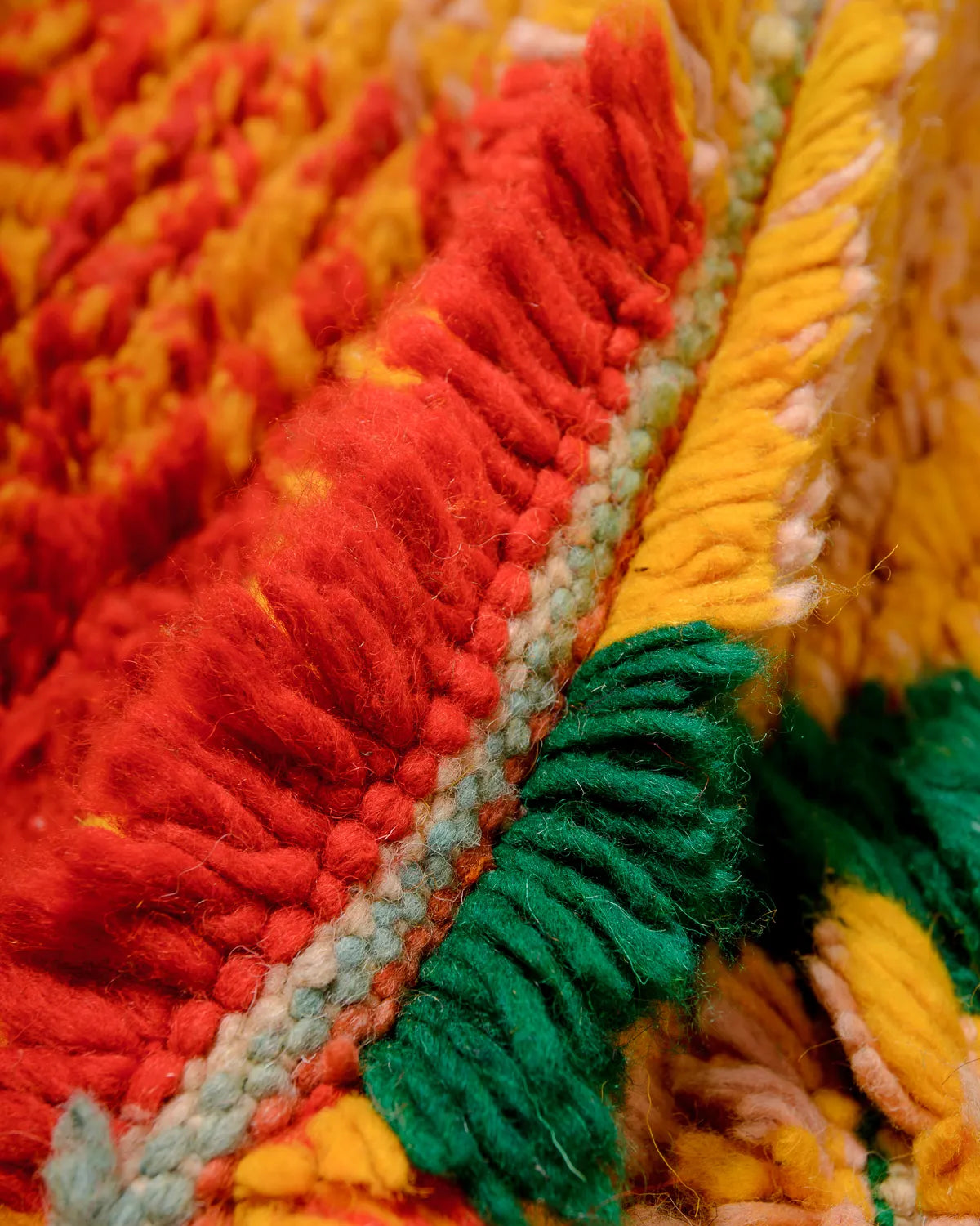 Detail of the wool in a vintage Berber rug in shades of dark orange, yellow and green.