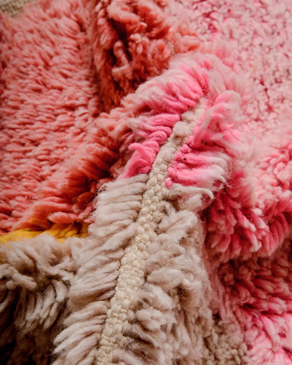 Detail of handwoven wool Berber rug featuring fluffy wool in shades of pink and yellow.