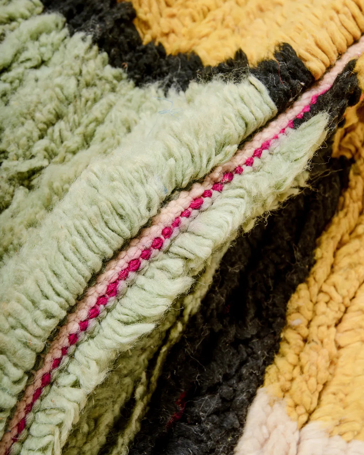 Detail of wool Berber rug from Morocco in shades of pistachio, yellow and black.
