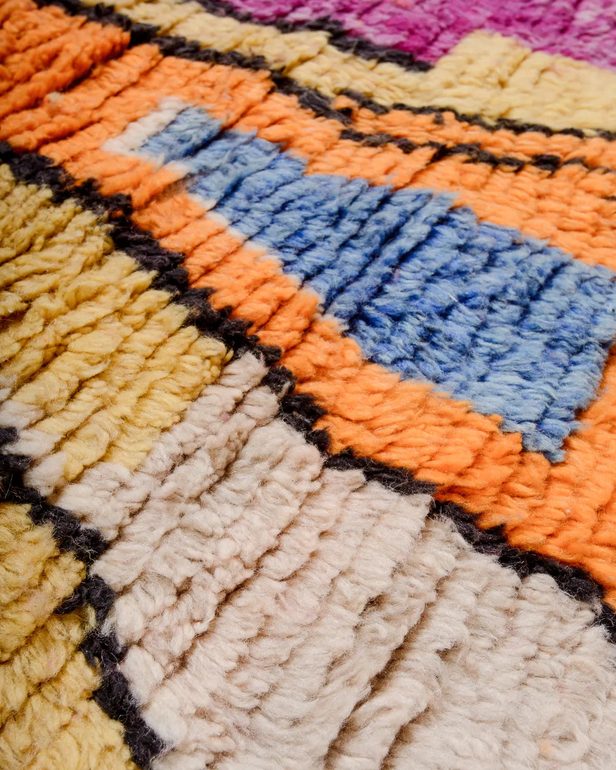 Detail of woolen rug texture in orange, blue, cream, yellow, black  and pink.  