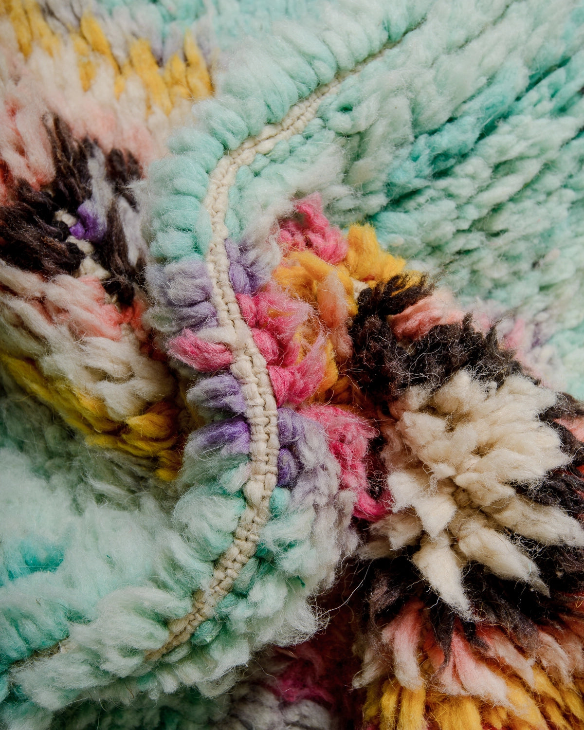 Detail of Berberlin Vintage Berber Rug made of fluffy turquoise wool with details in pink, lavender, brown, yellow and cream.