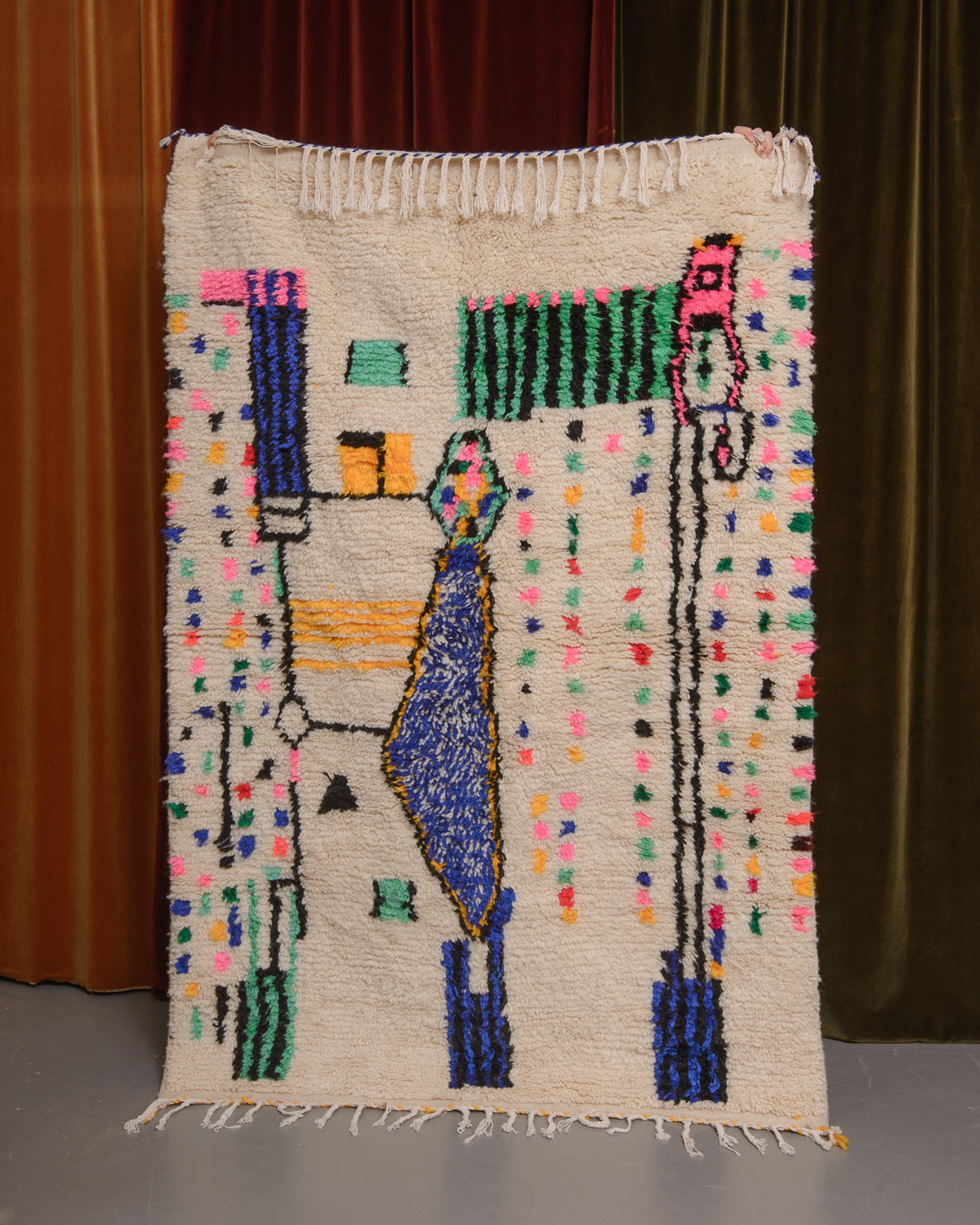 Azilal rug held in front of velvet curtains. 