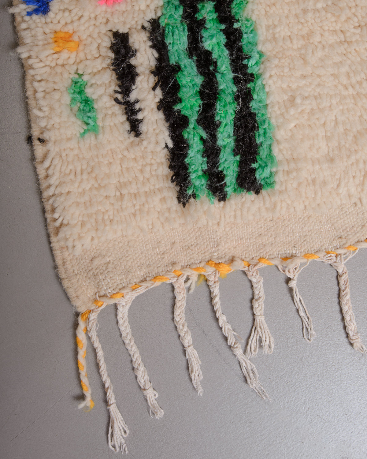 Corner of Berberlin azilal rug with white cotton tassels.