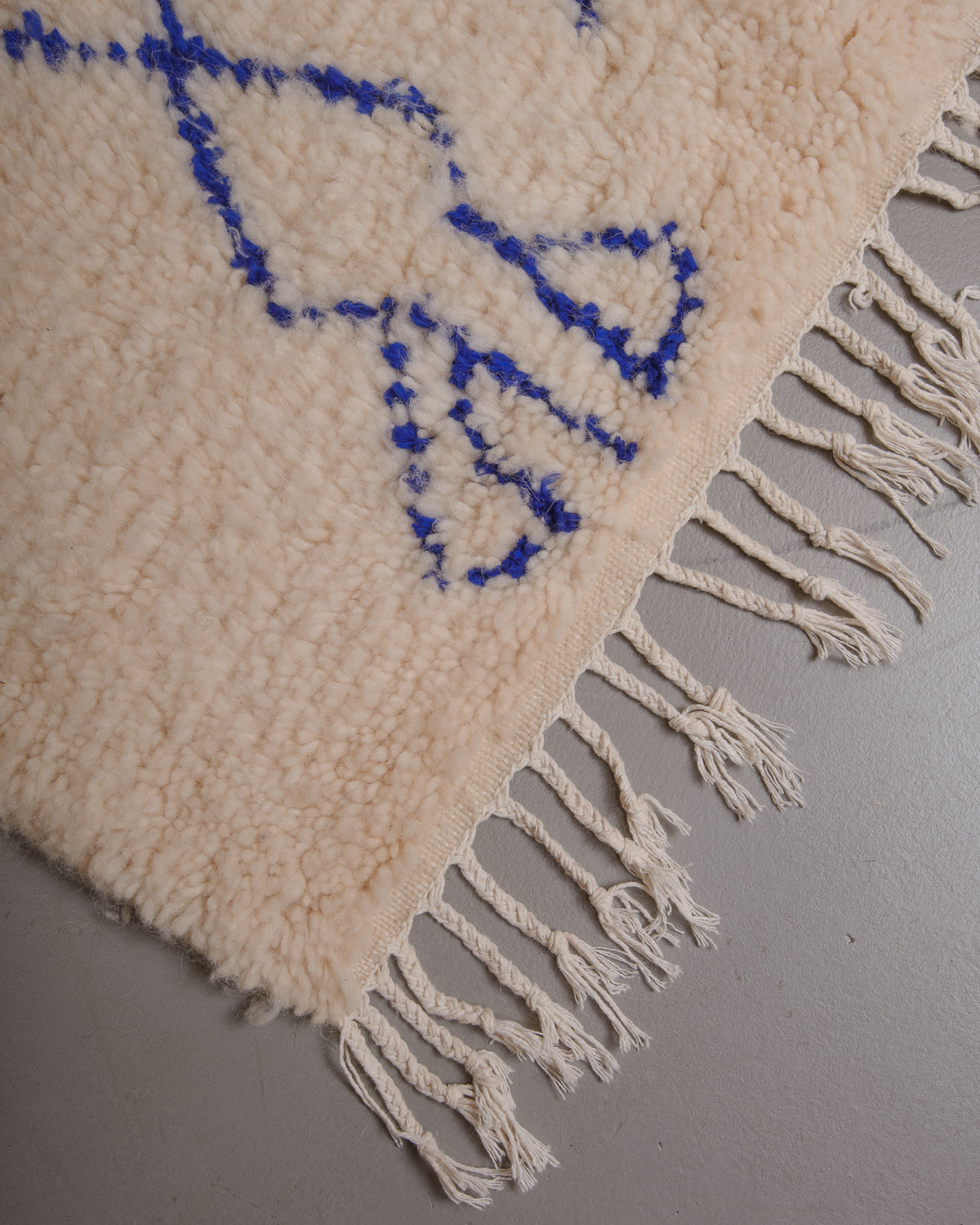 Corner of Berberlin azilal rug with white cotton tassels.