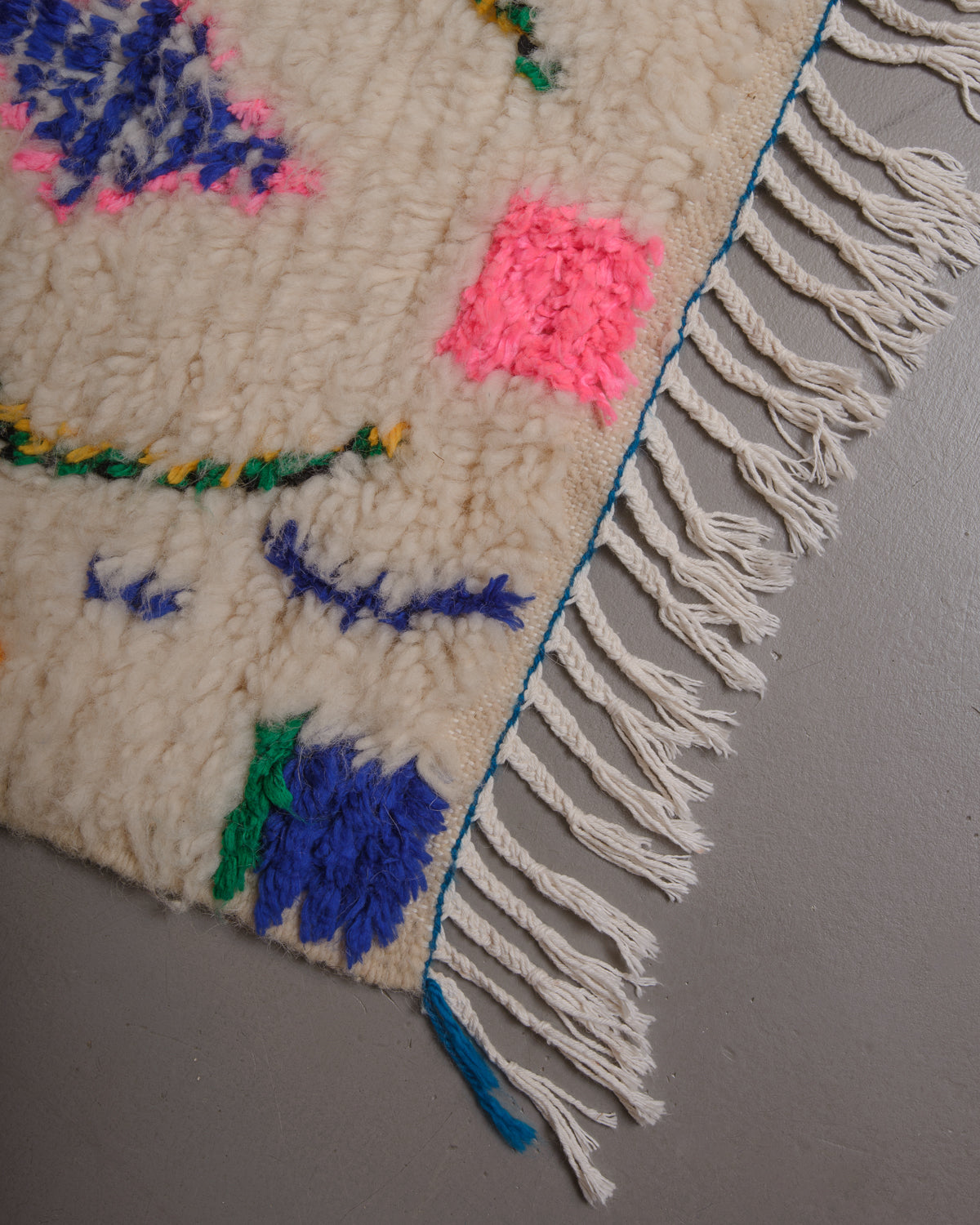 Corner of Berberlin azilal rug with white cotton tassels.