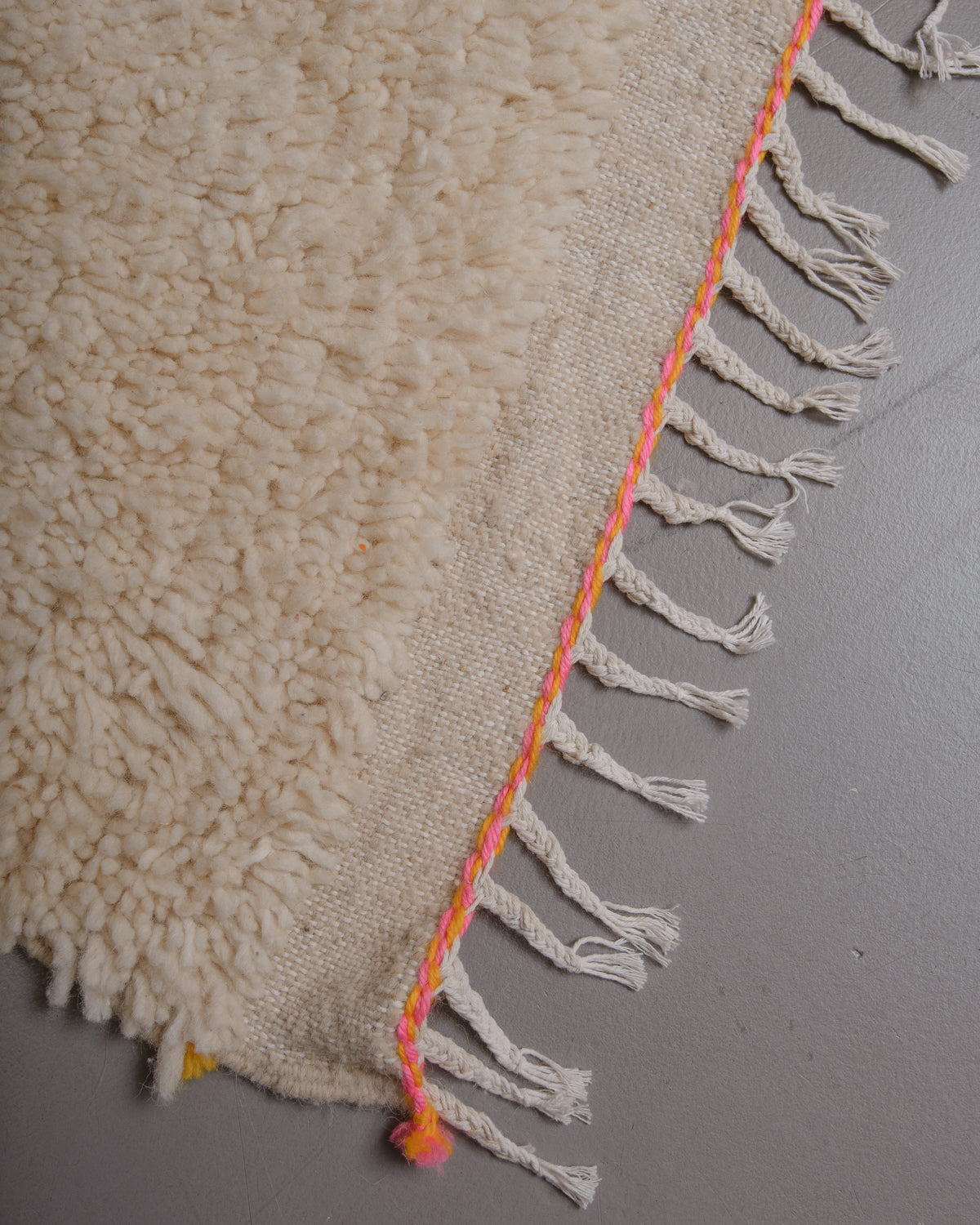 Corner of Berberlin azilal rug with white cotton tassels.