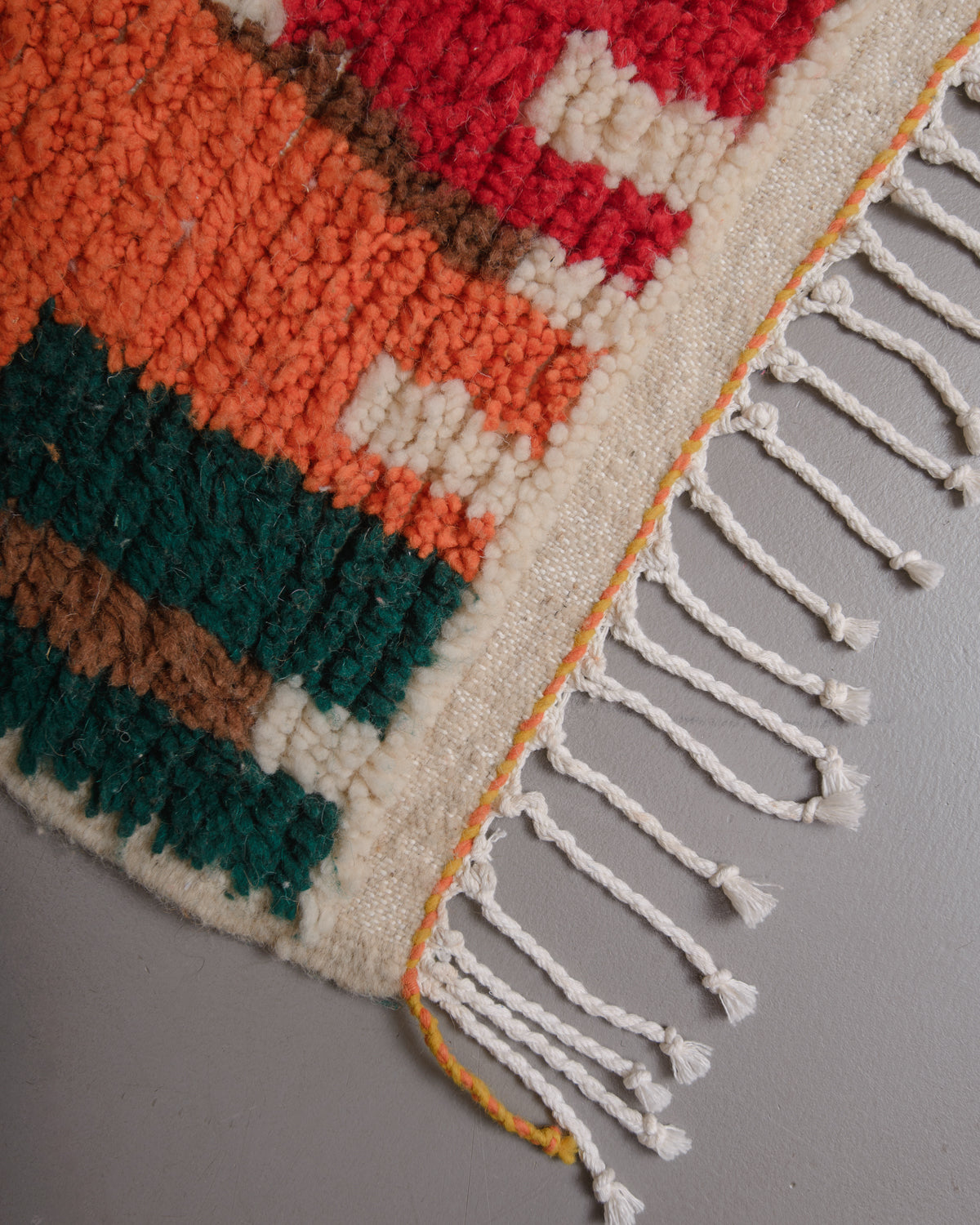 Corner of Berberlin azilal rug with white cotton tassels.