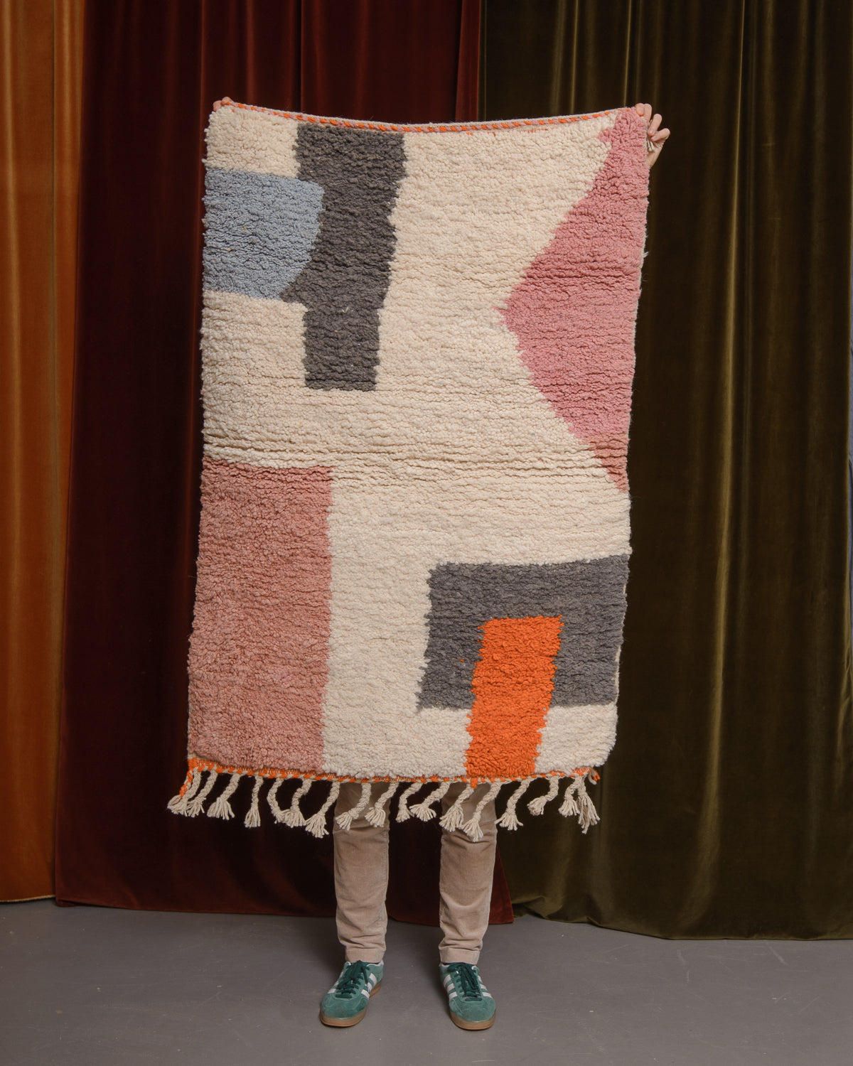 Berberlin Special Edition Beniourain rug held up in front of a velvet curtain.