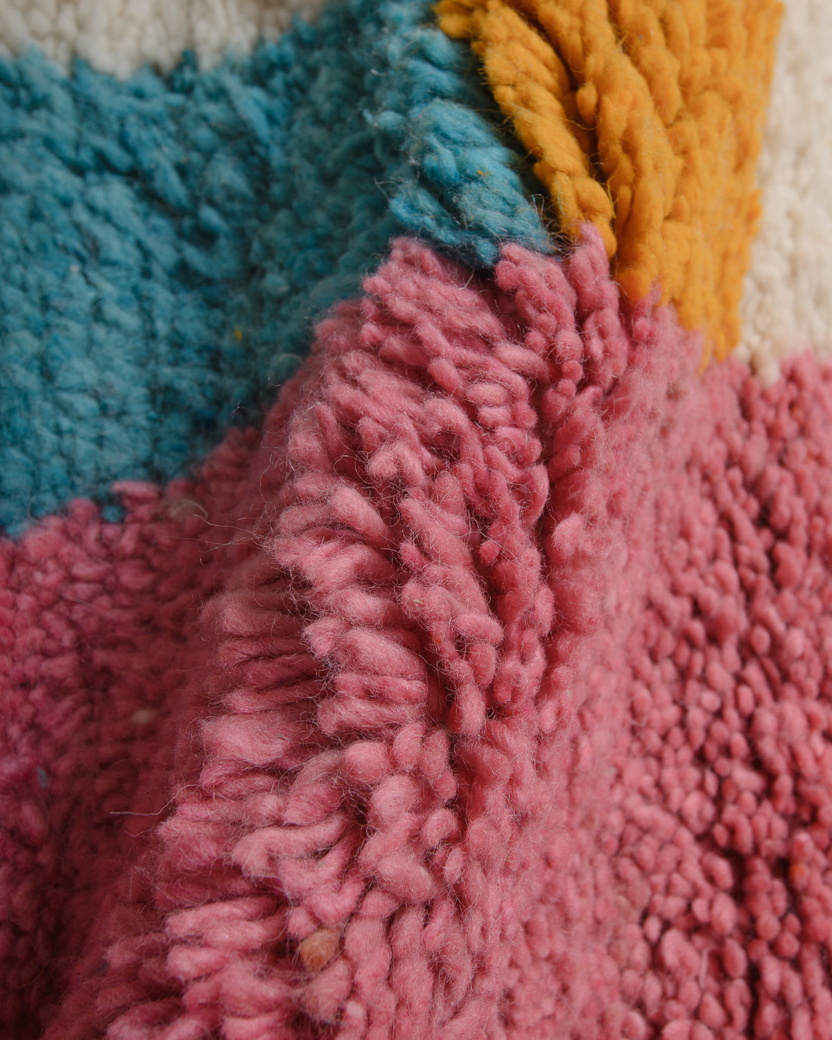Close up of wool rug with blue, yellow and pink. 