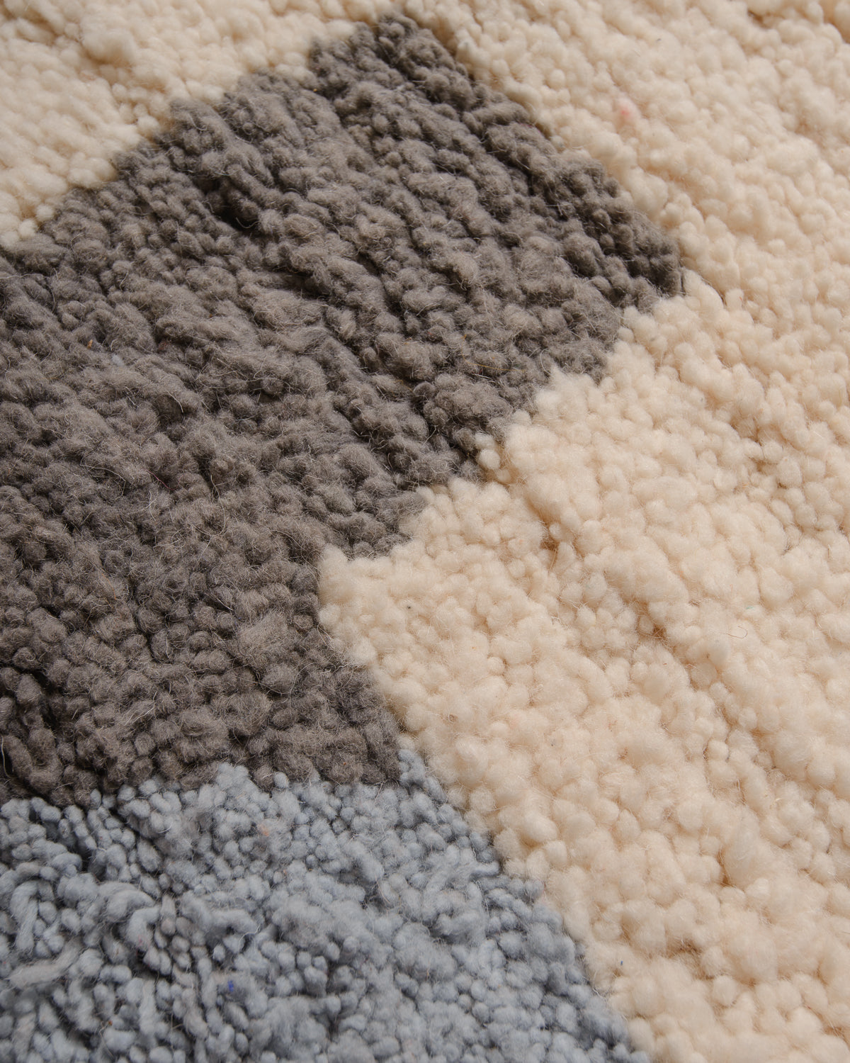 Close up of wool rug with cream, grey and light blue.