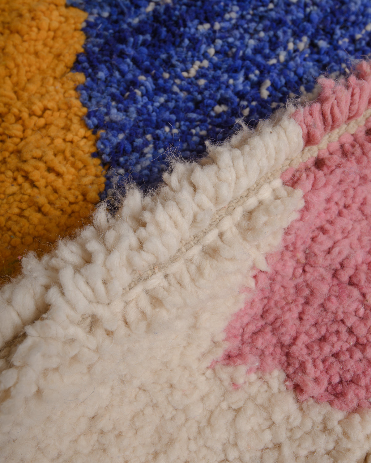 Close up of wool rug with blue, yellow and pink. 