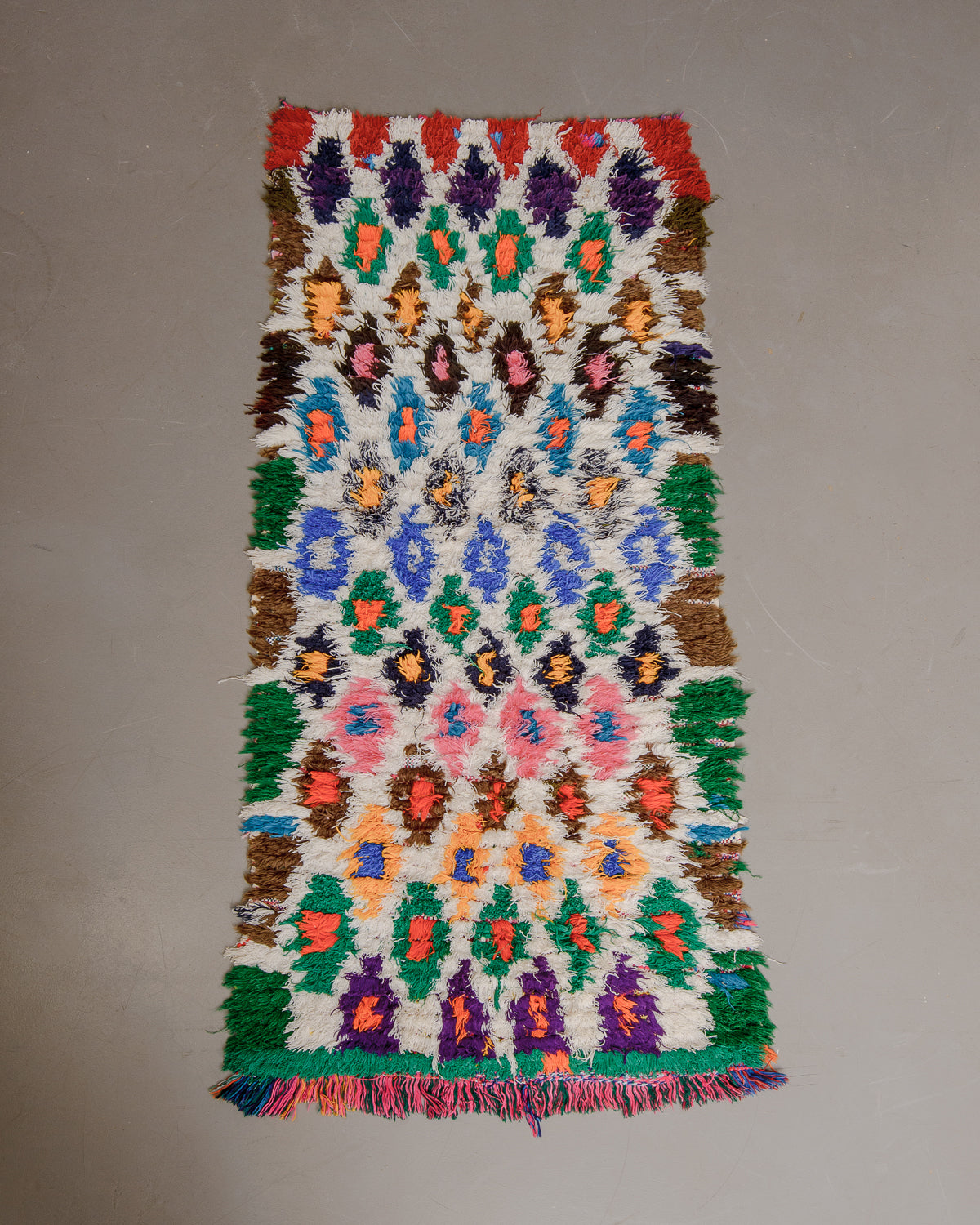 Vintage Berberlin boucherouite runner rug on grey floor.