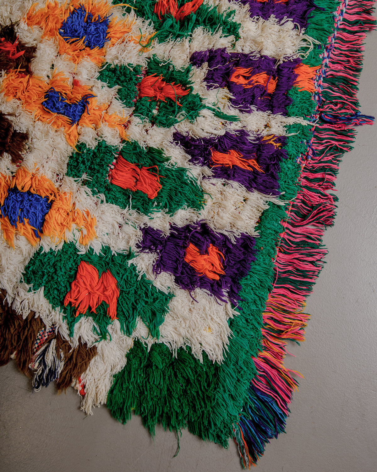 Corner of colourful shaggy rug with multicoloured cotton fringe.