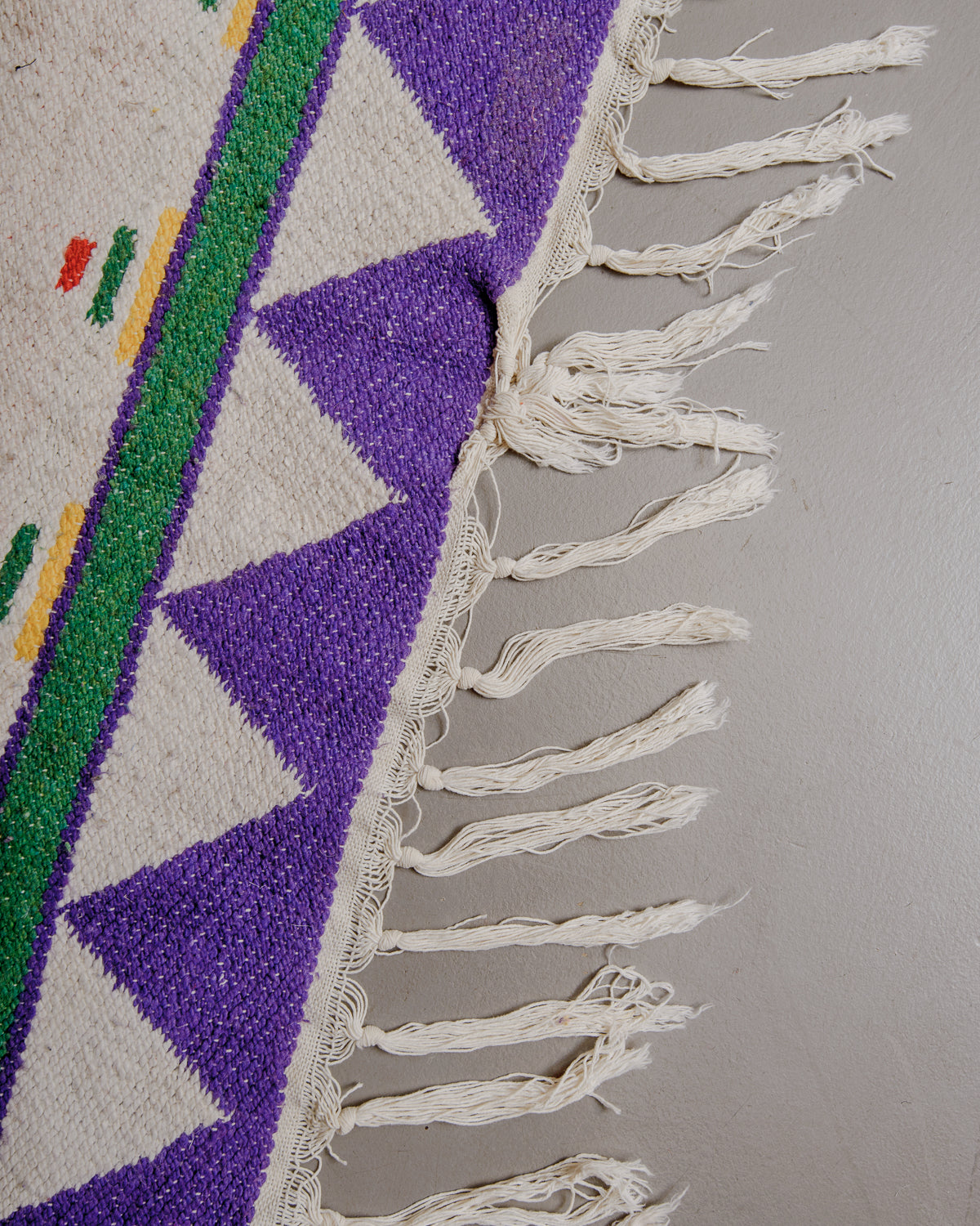 Edge of rug with white cotton tassels.