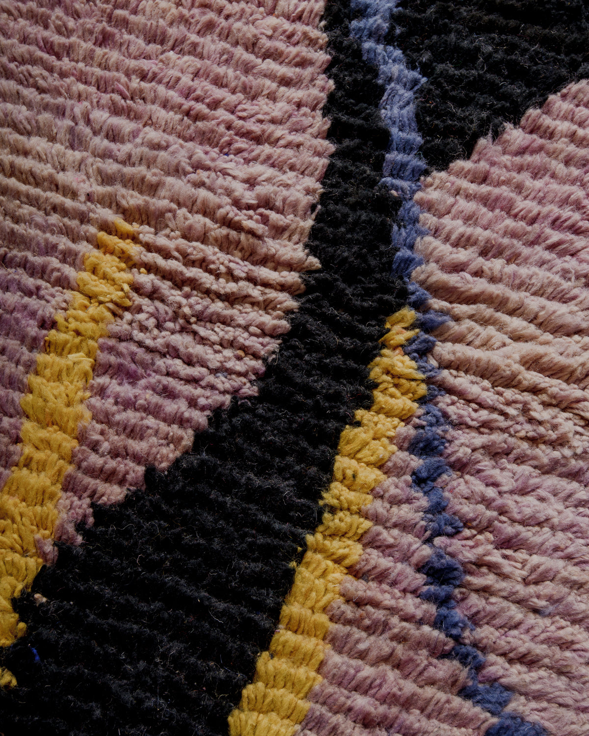 Surface of wool boujaad rug in mauve, black, yellow and blue.
