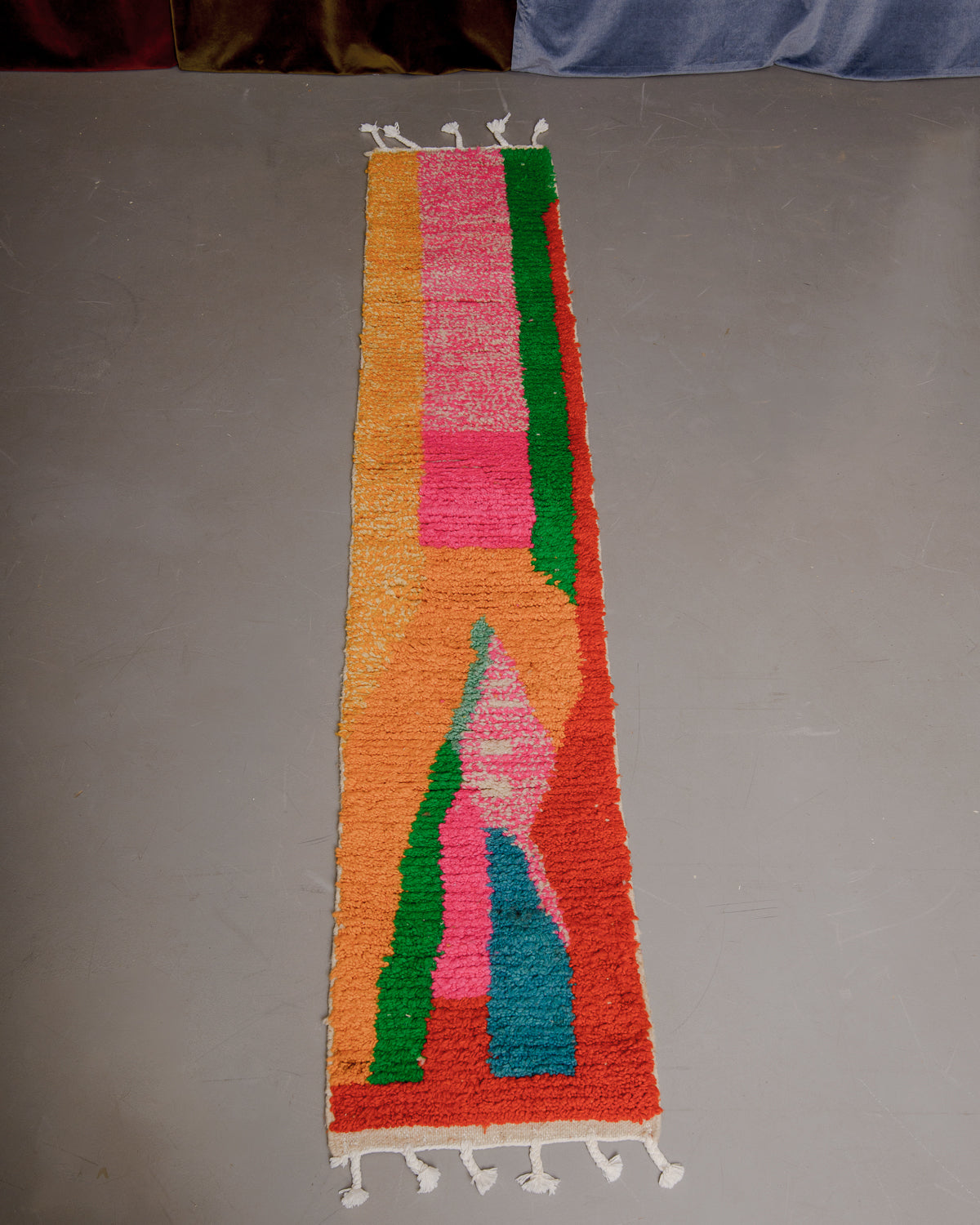 Vintage Berberlin boujaad runner rug on grey floor in front of velvet curtains.