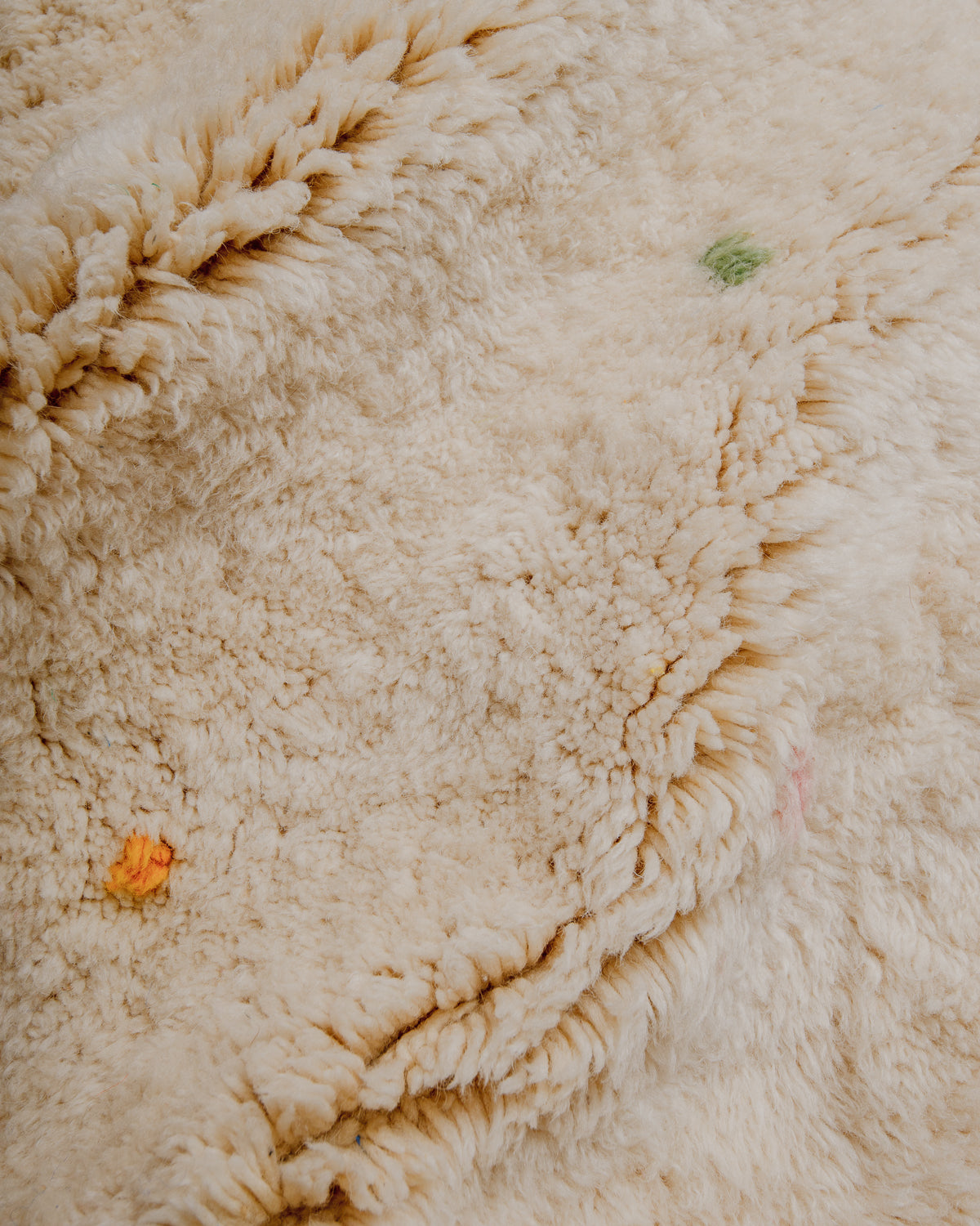 Surface of cream wool rug showing plush texture.