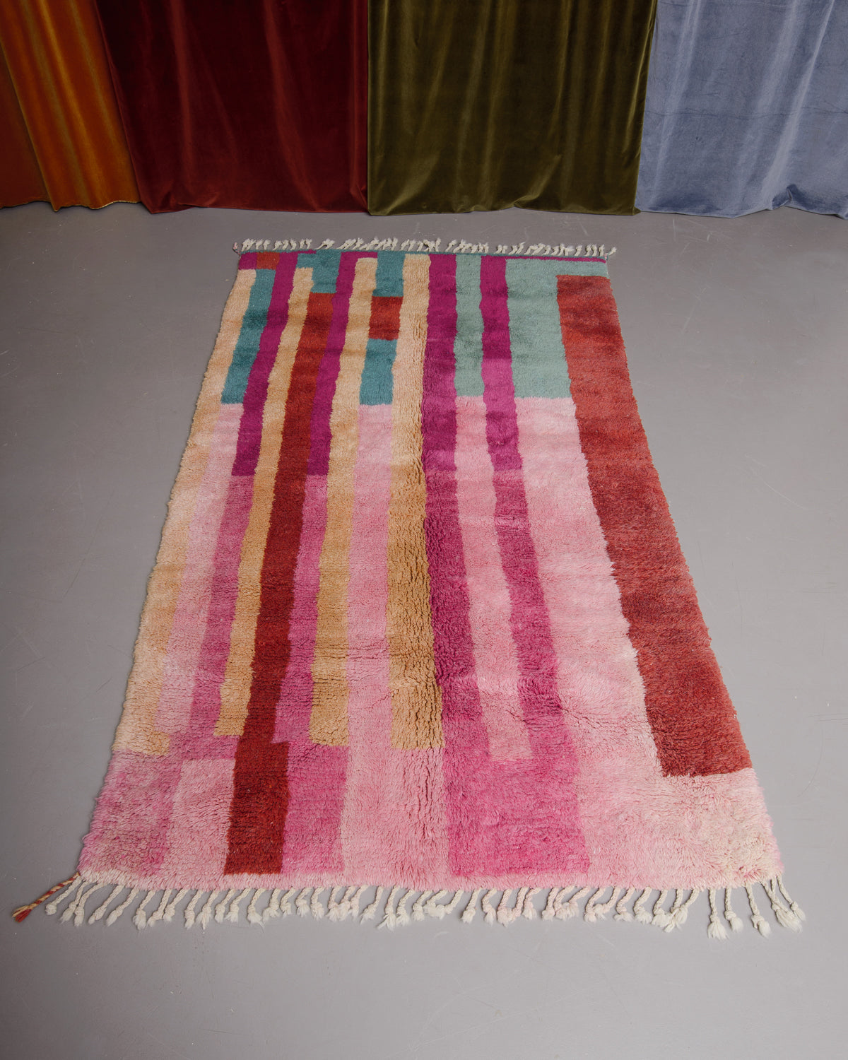 Berberlin Finest beniourain rug on grey floor in front of velvet curtains.