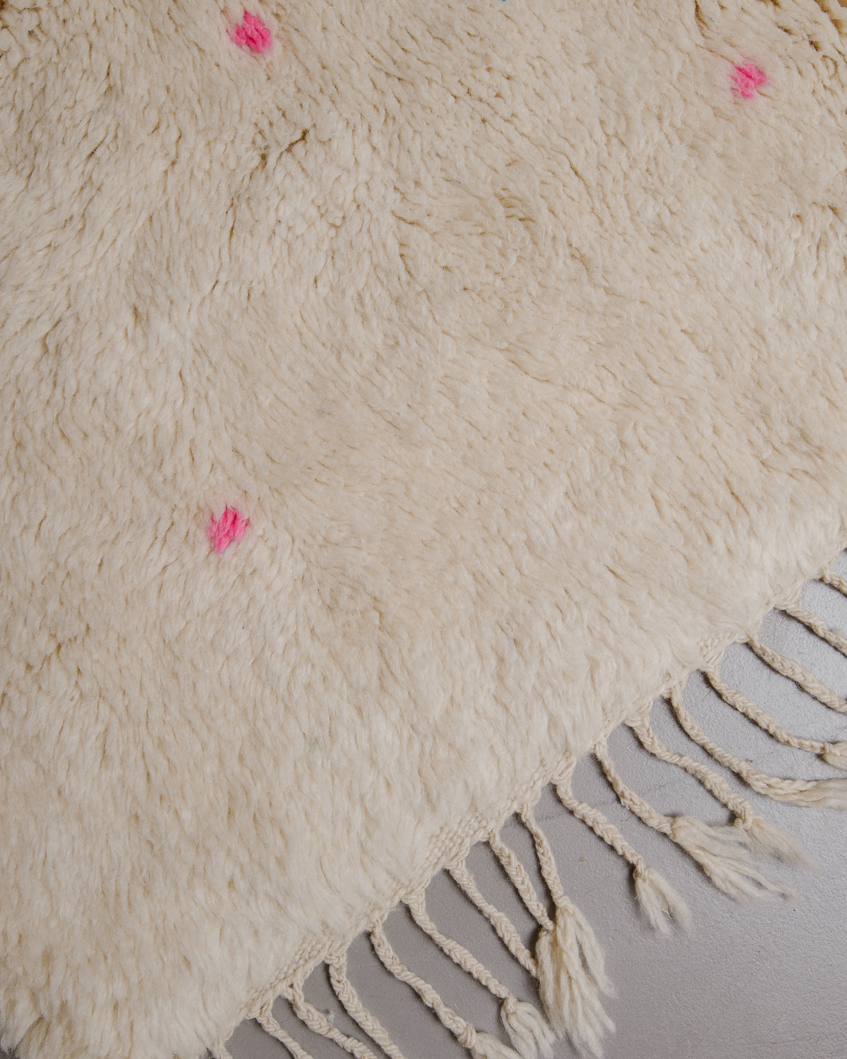 Edge of cream beniourain rug with natural wool tassels and neon pink polka dots.