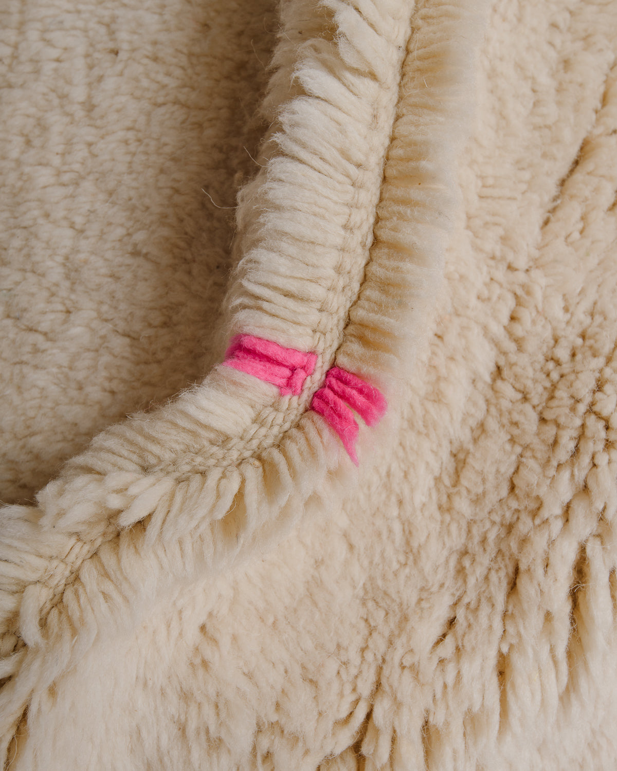 Close up of plush wool pile in cream and neon pink.