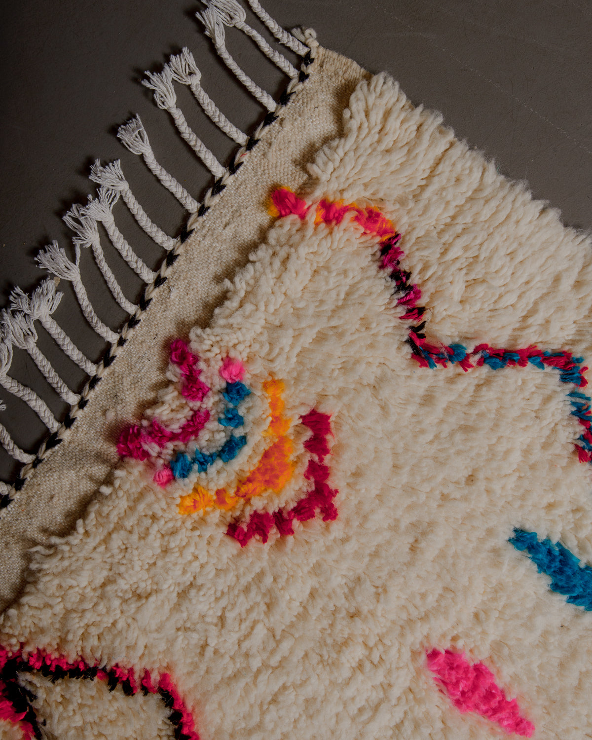 Corner of azilal rug with white cotton tassels.