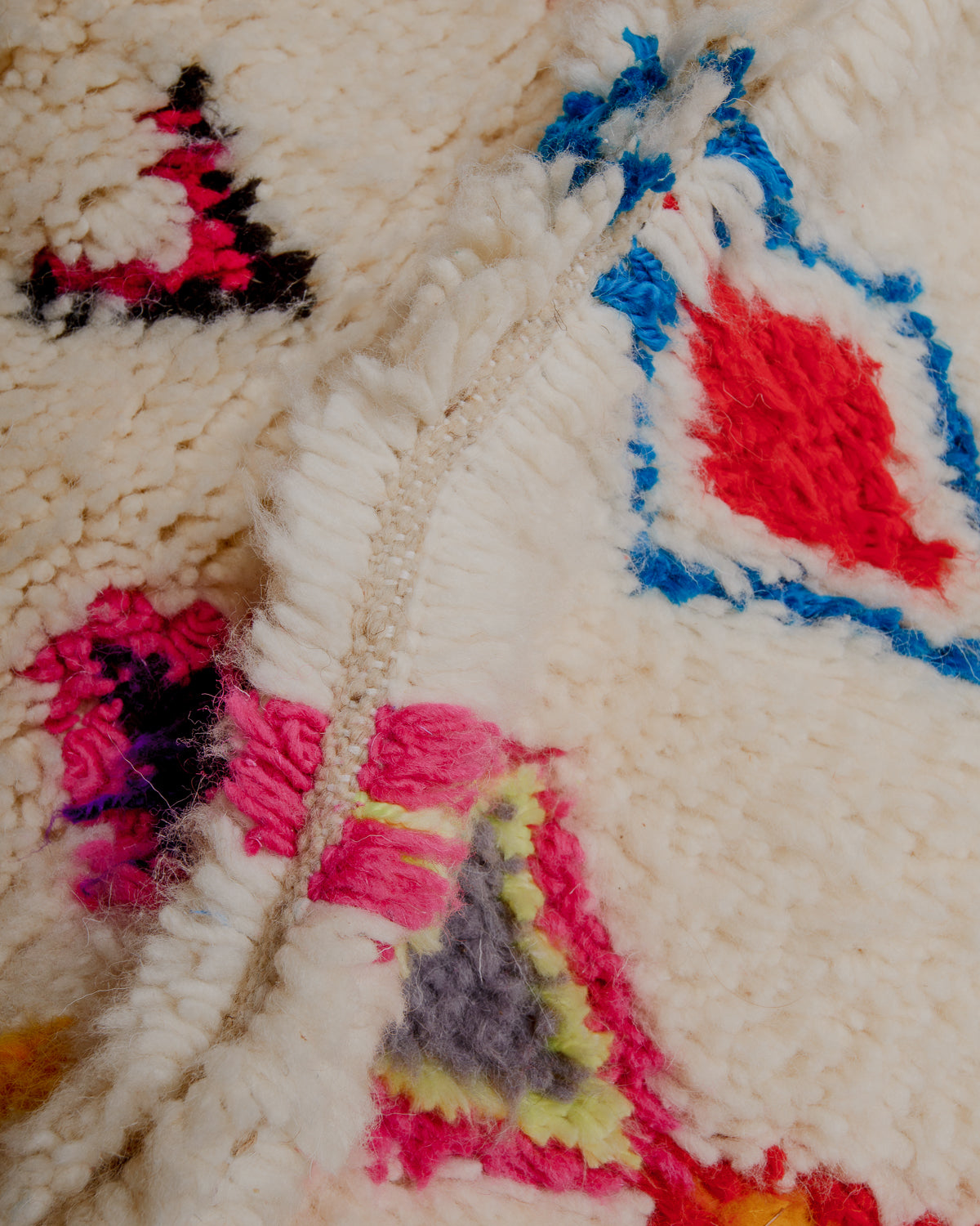Close up of cream wool rug with colourful details in wool and cotton.
