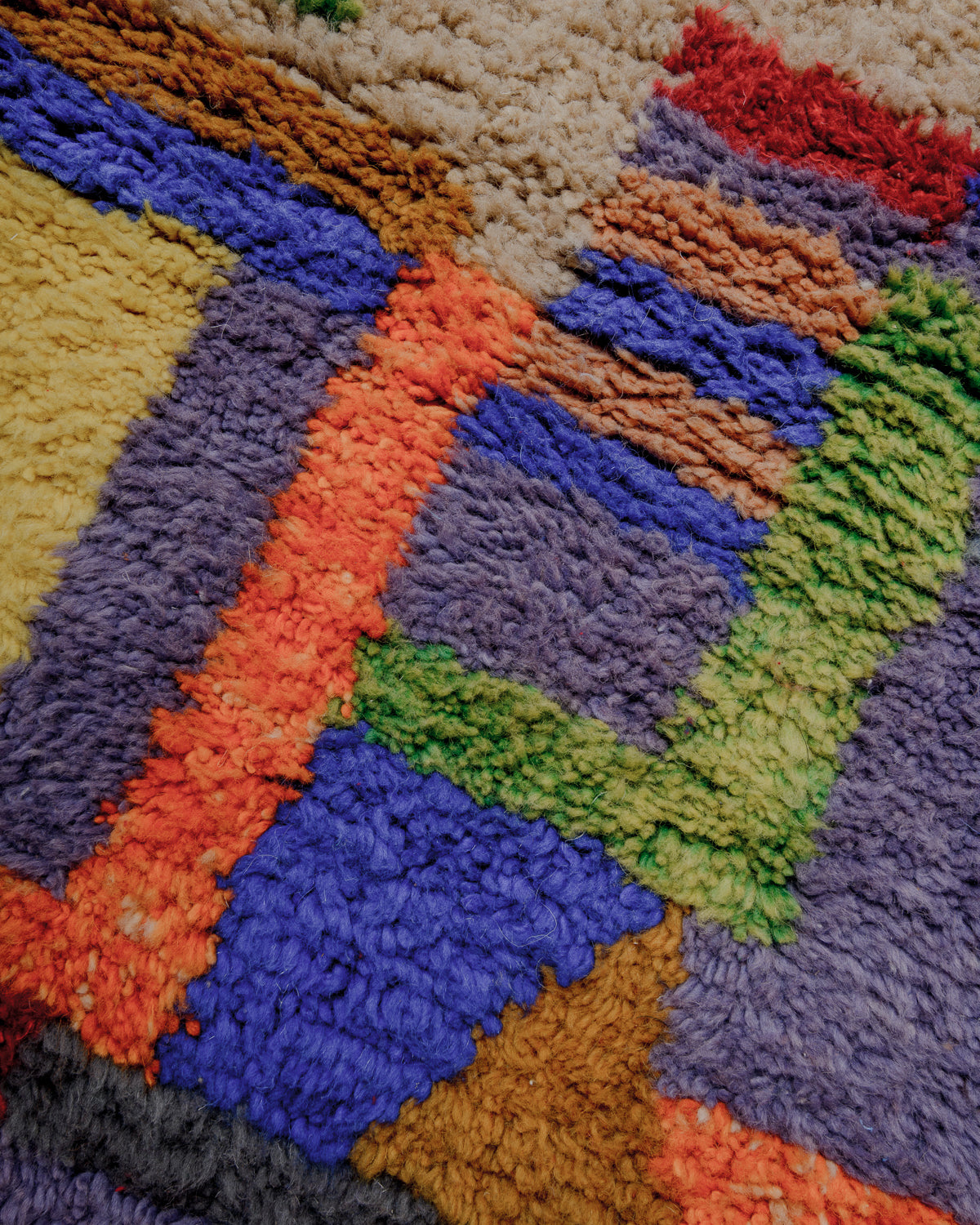 Surface of rug with orange, green, purple, blue, yellow and brown wool.