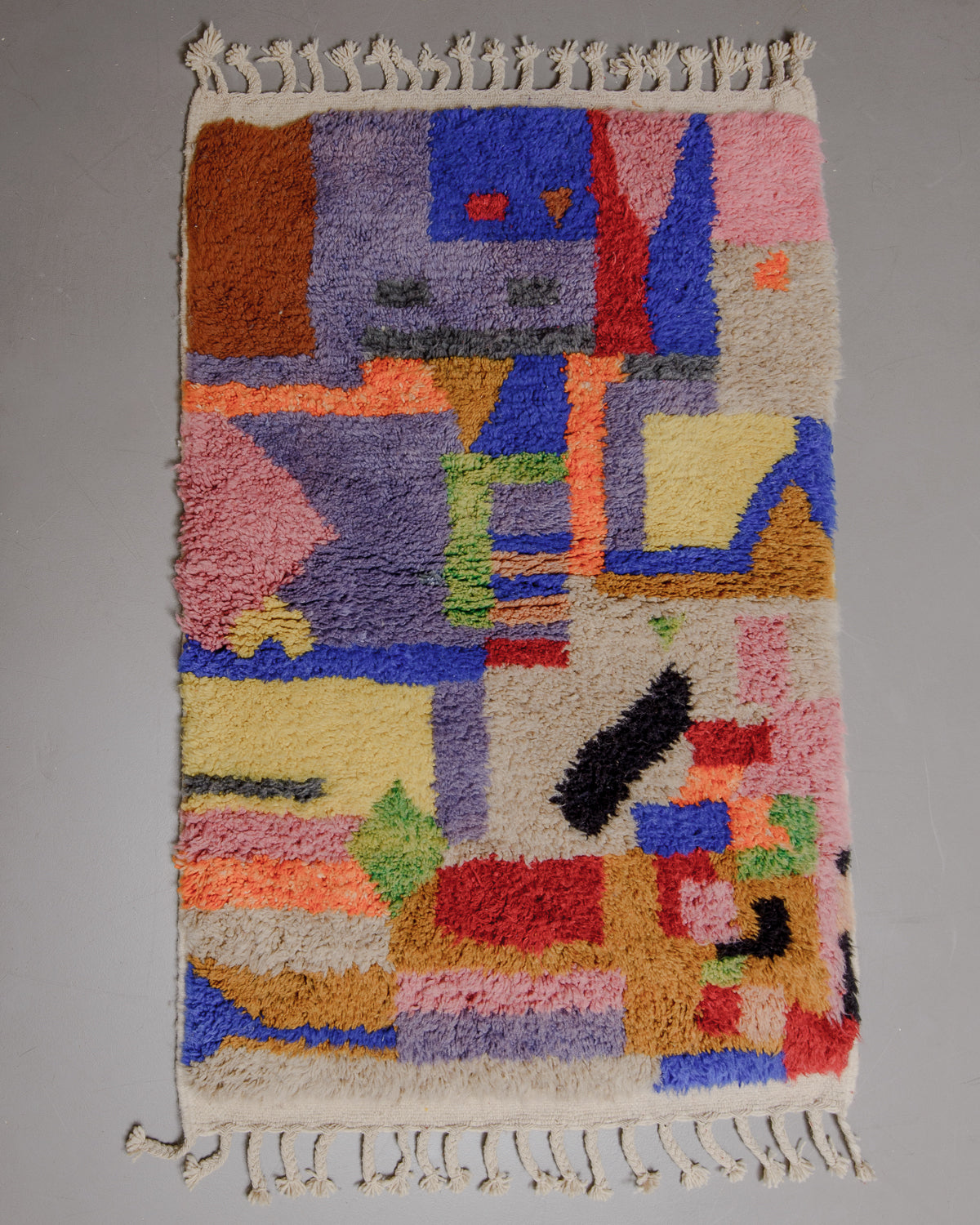 Berberlin Beniourain rug with colourful geometric pattern on grey floor.