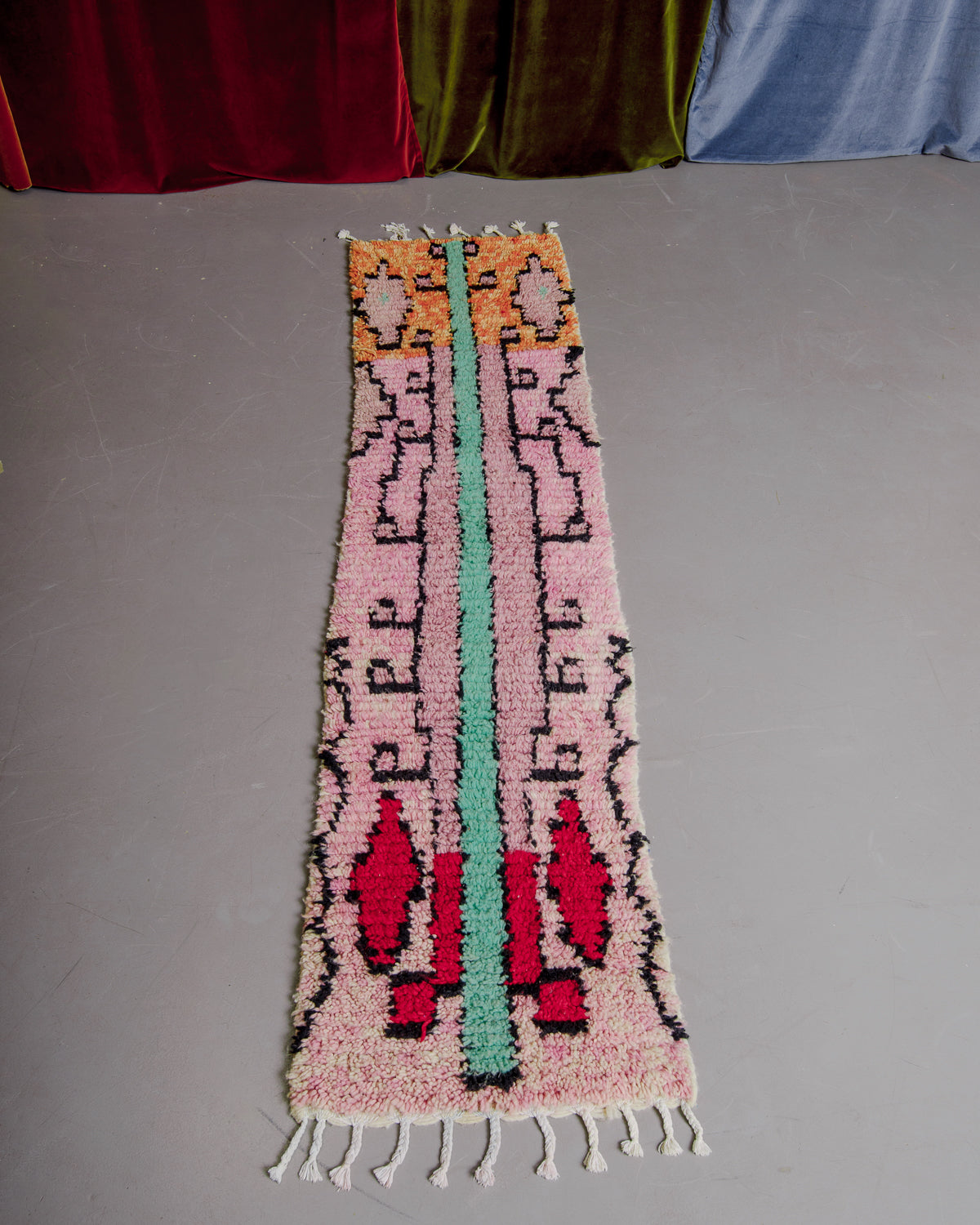 Vintage Berberlin boujaad runner rug on grey floor in front of velvet curtains.