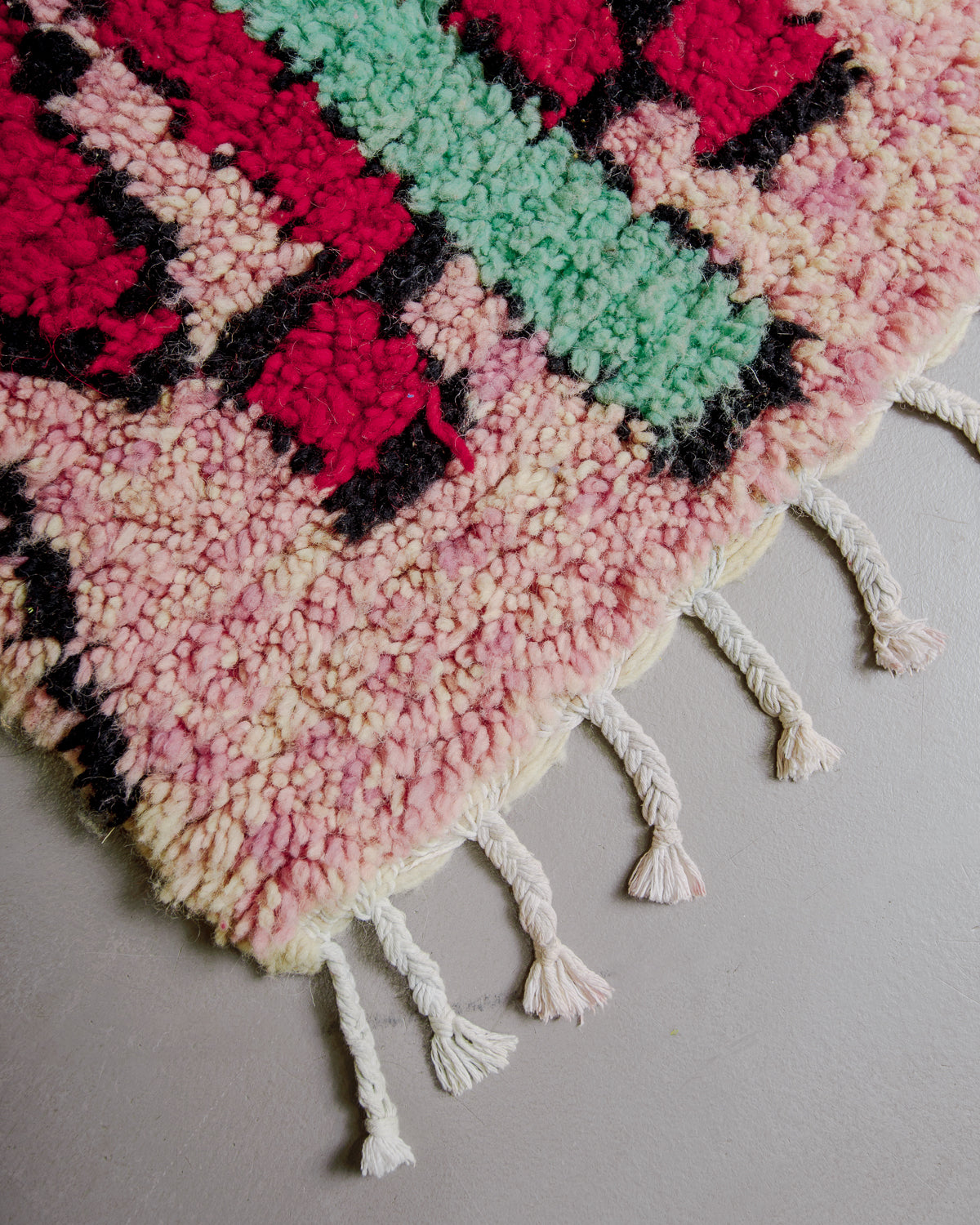 Corner of boujaad rug with  pink, red and turquoise wool.