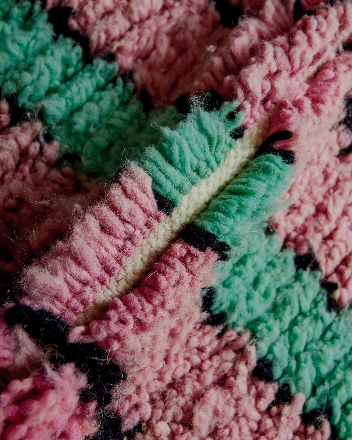 Texture of boujaad rug with black, pink and turquoise wool.