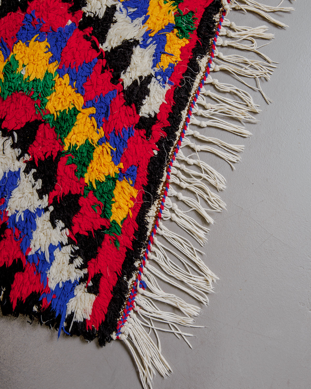 Corner of boucherouite rug with cotton tassels.