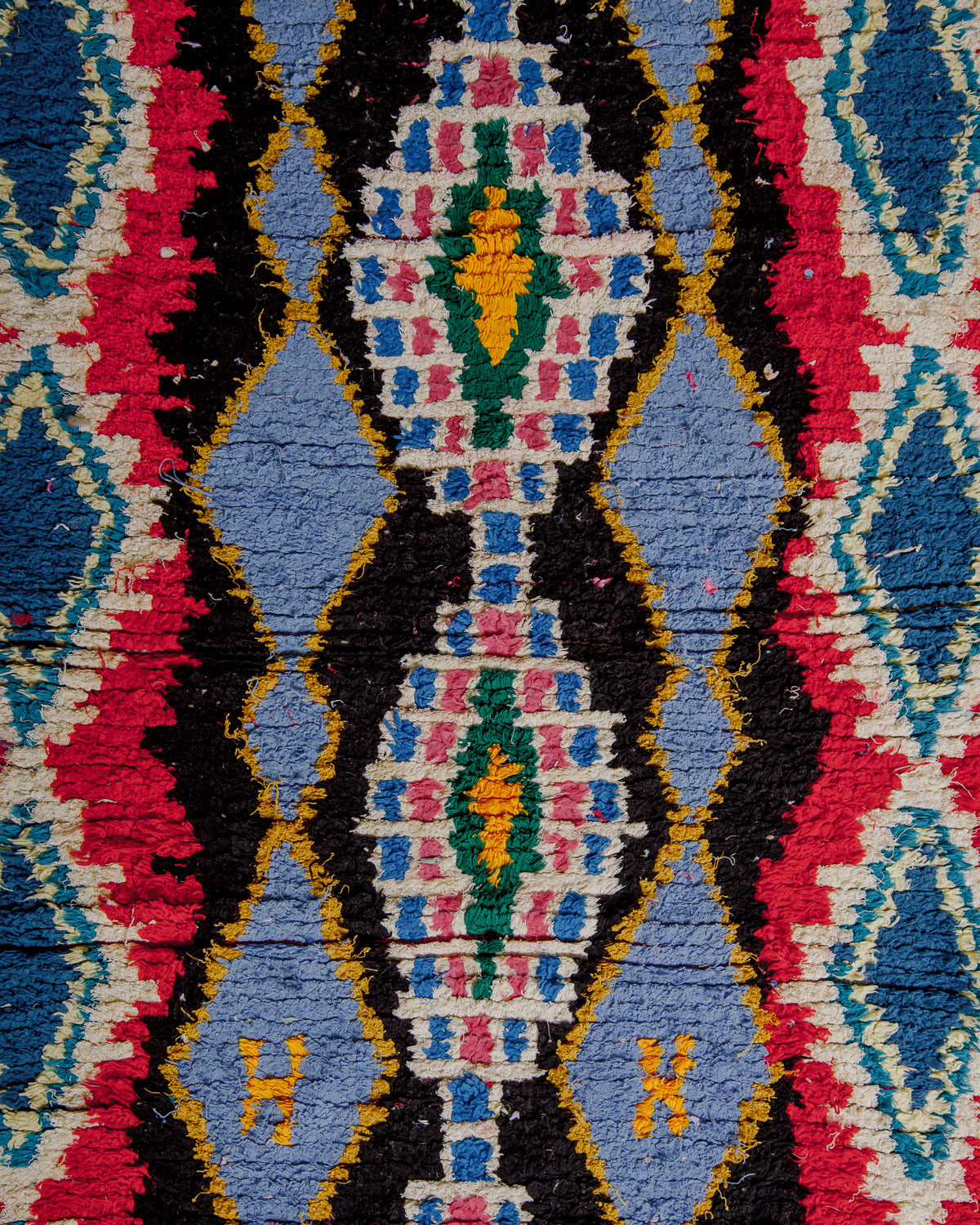Surface of boucherouite rug with colourful cotton and bold pattern.