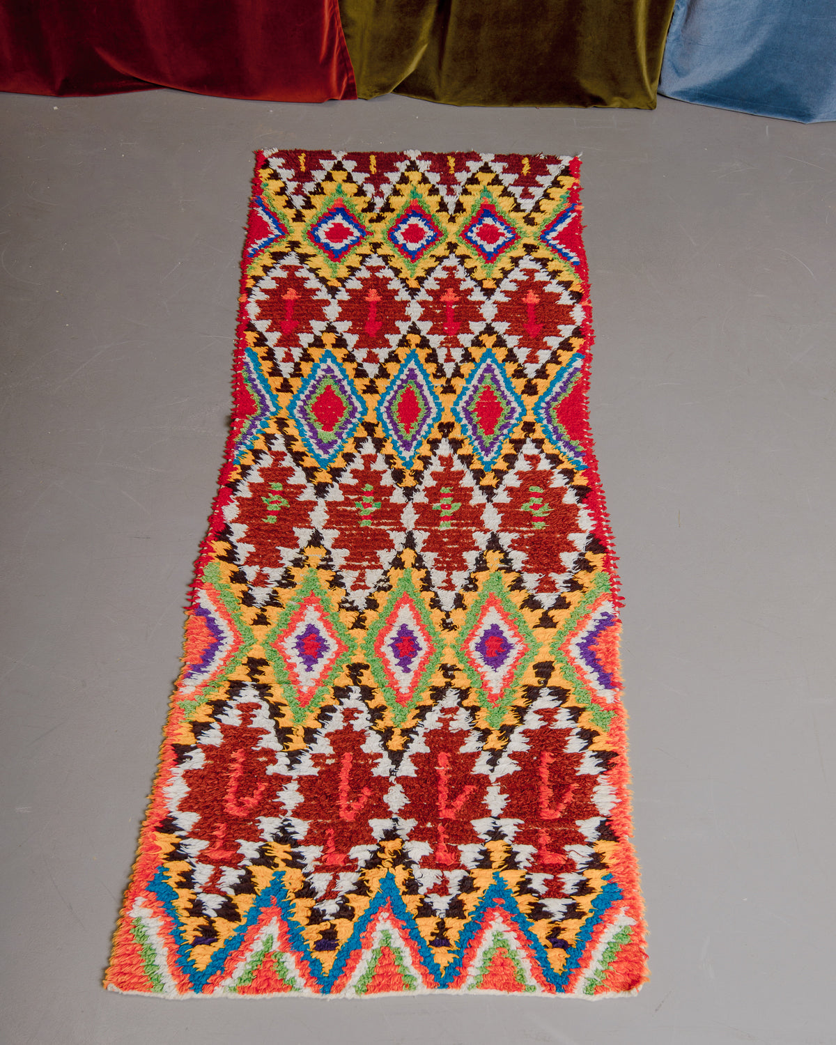 Vintage Berberlin boucherouite runner rug on grey floor.