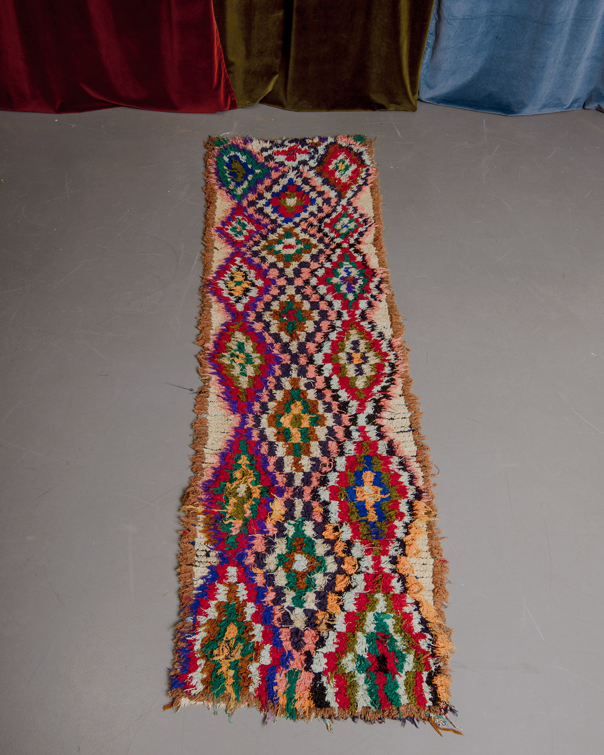Vintage Berberlin boucherouite runner rug on grey floor.