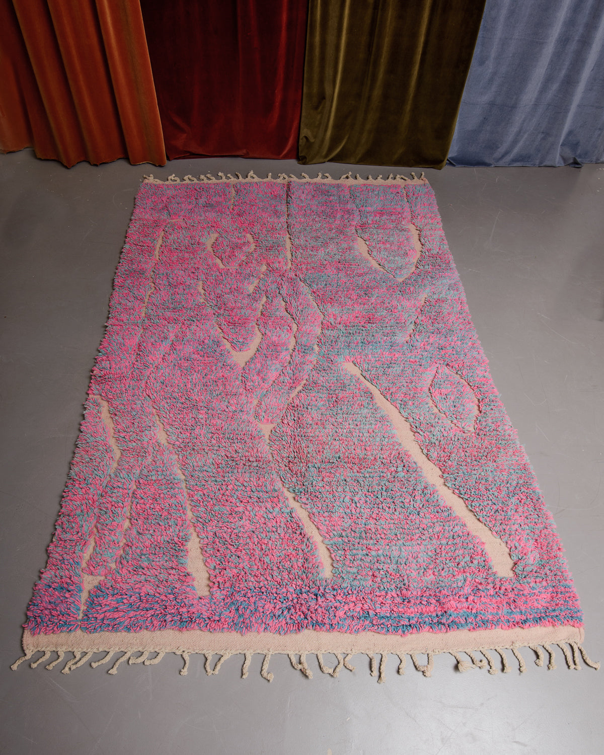 Berberlin Boujaad rug in pink and blue speckled wool with organic woven lines on in front of velvet curtains.