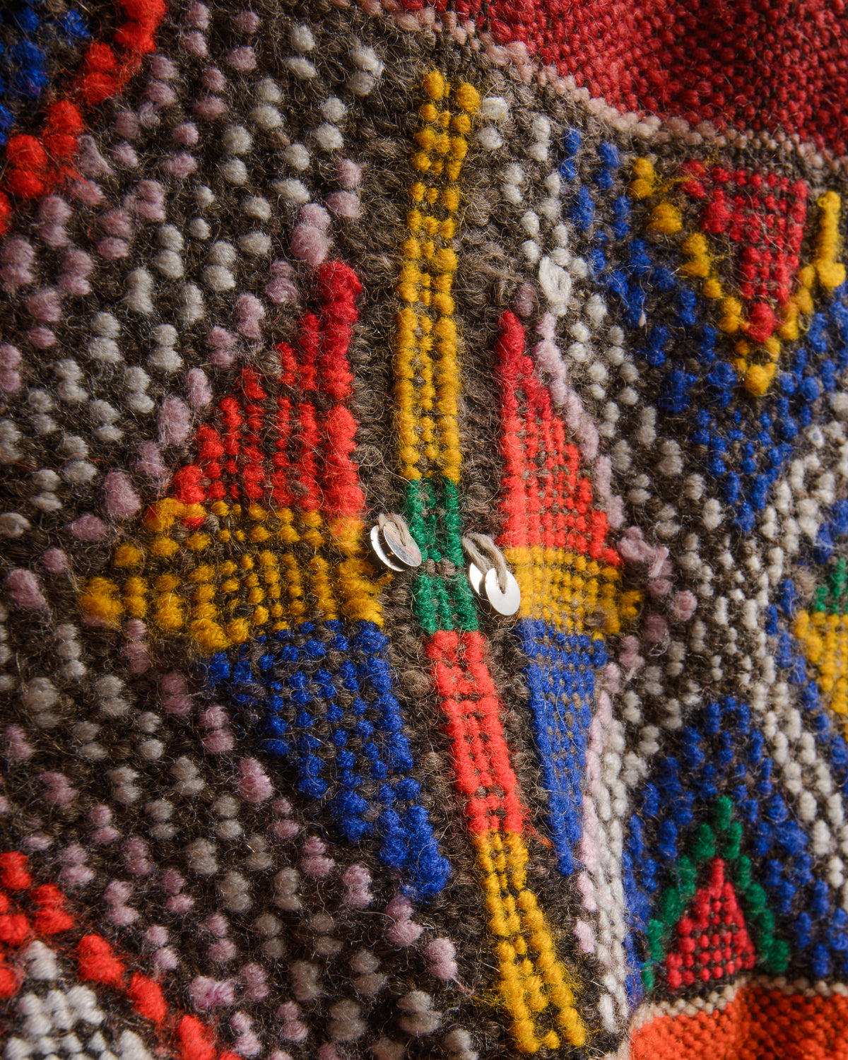Surface details of colourful vintage kelim rug with silver sequin embellishments.