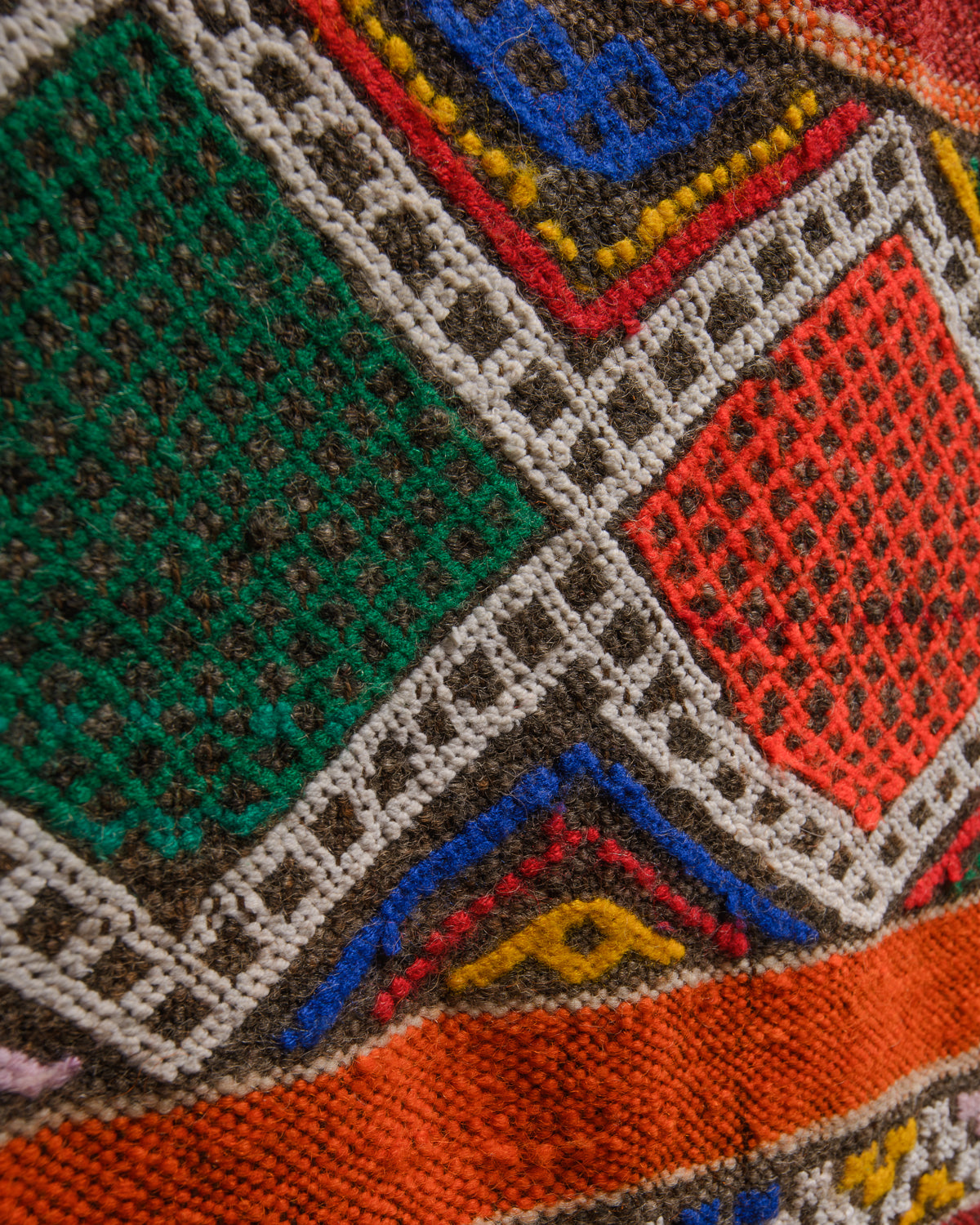Surface details of colourful vintage kelim rug with orange, brown, green, blue, yellow and white.
