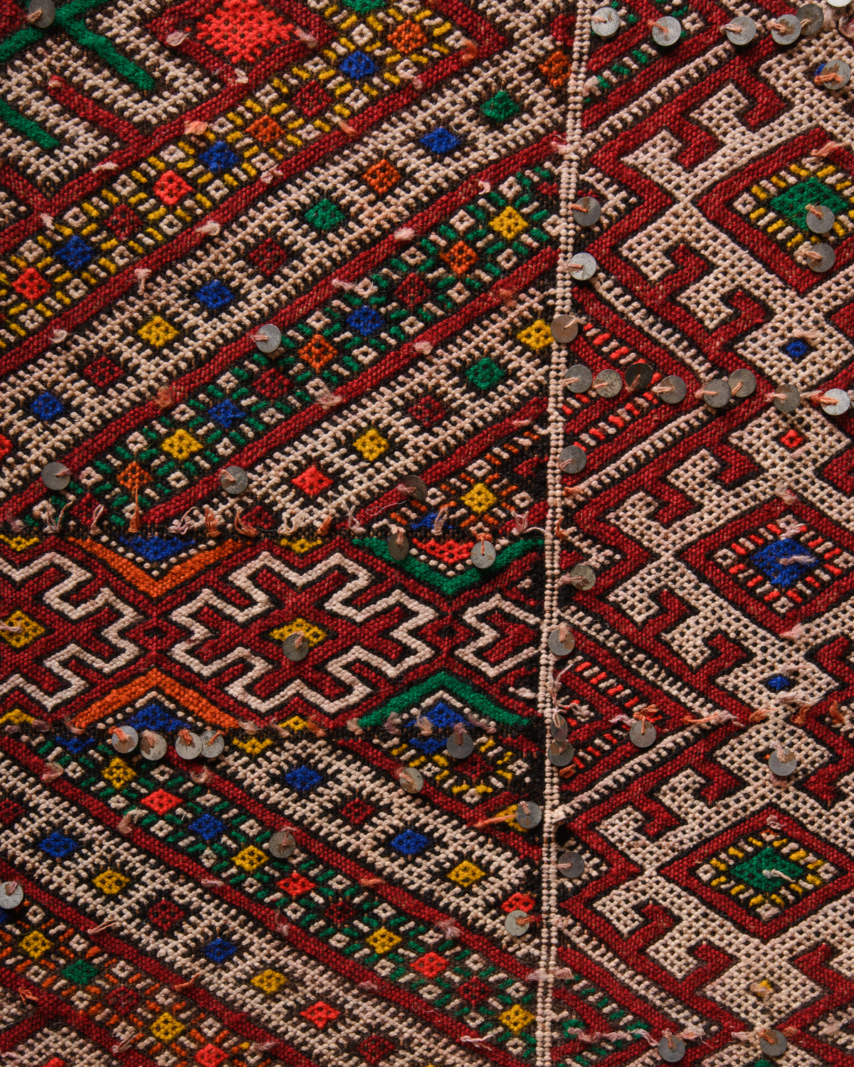 Surface details of colourful vintage kelim rug with silver sequin embellishments.
