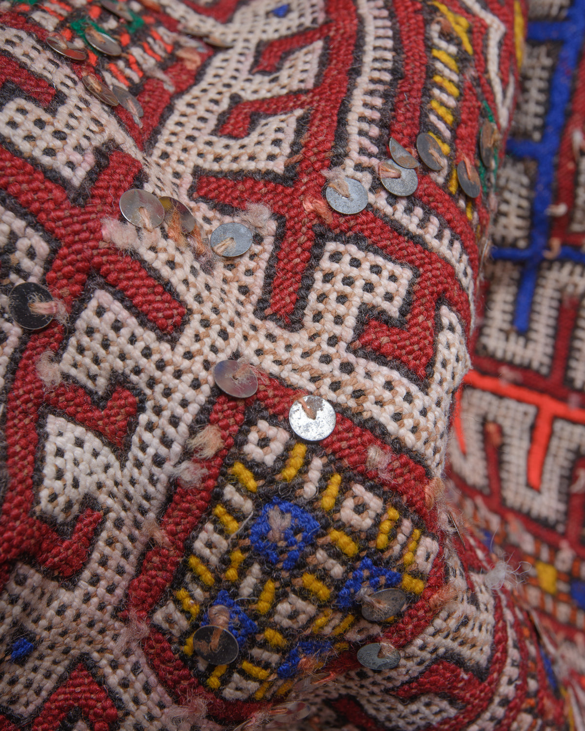 Surface details of colourful vintage kelim rug with silver sequin embellishments.